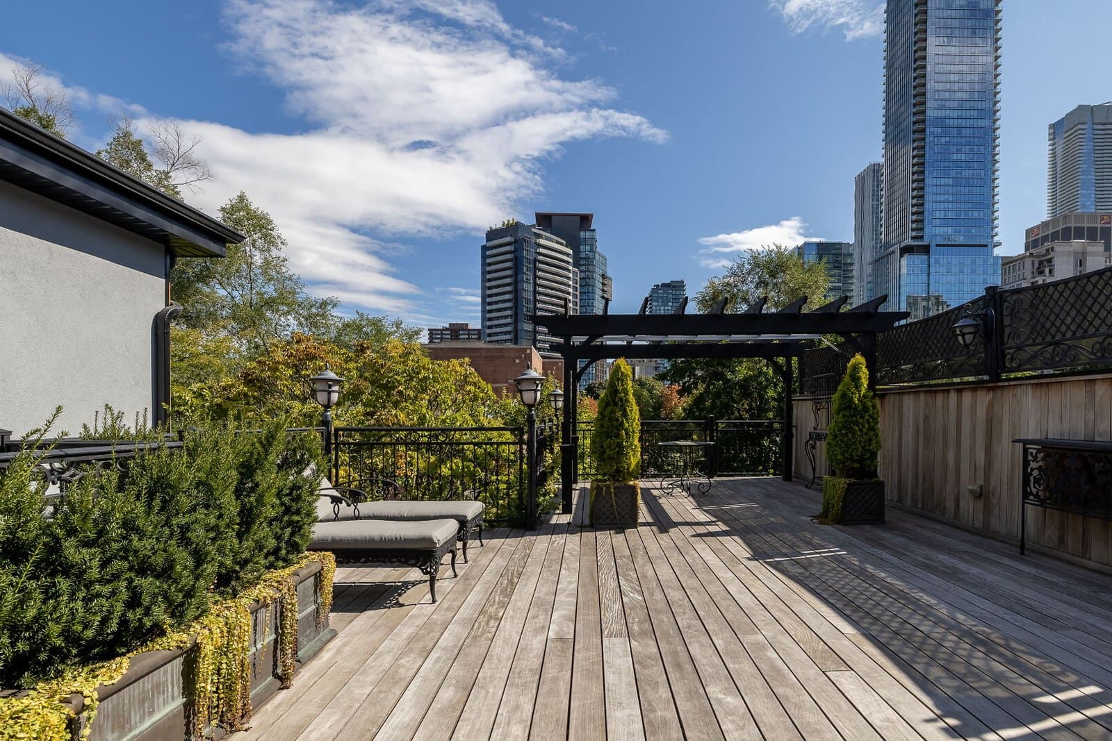 Rooftop terrace in wood decking with a pergola and the city skyline beyond