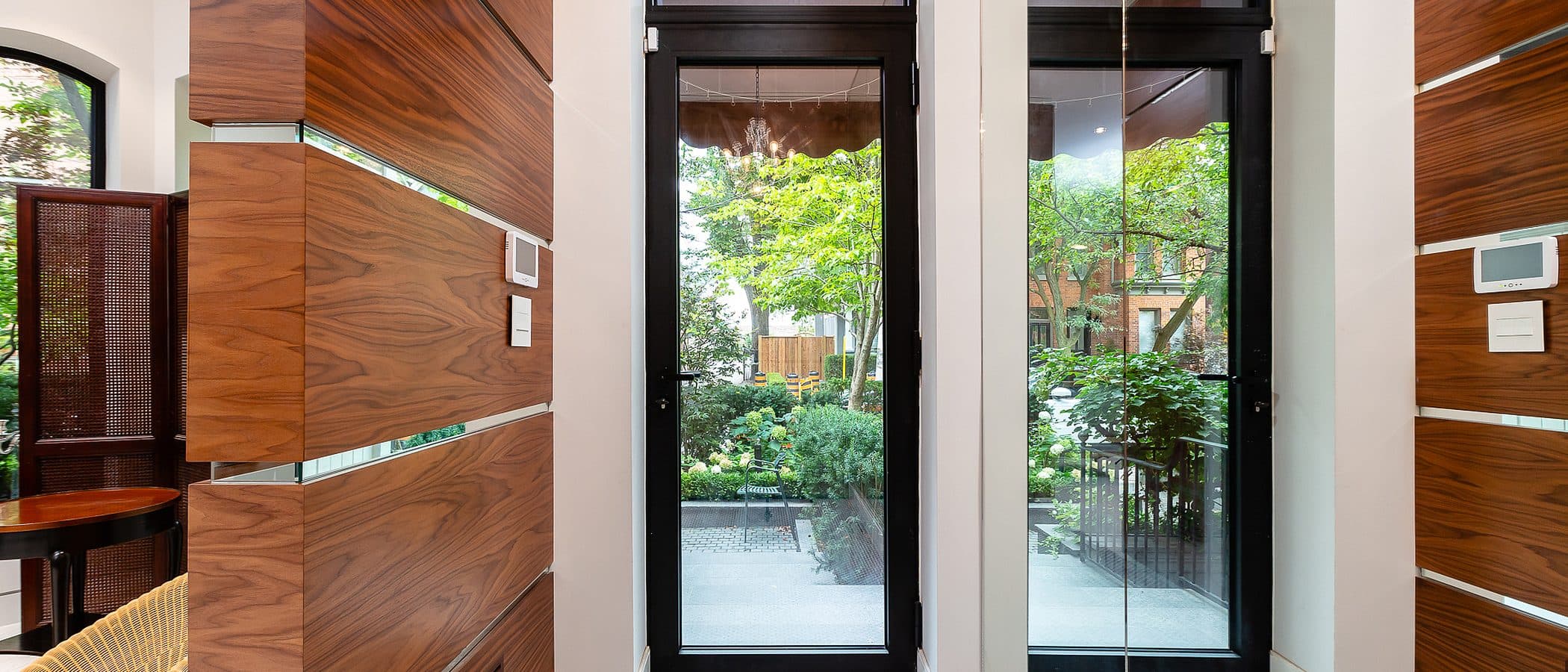 Walnut paneled vestibule with penny tile flooring and black framed glass doors opening to a rear garden.