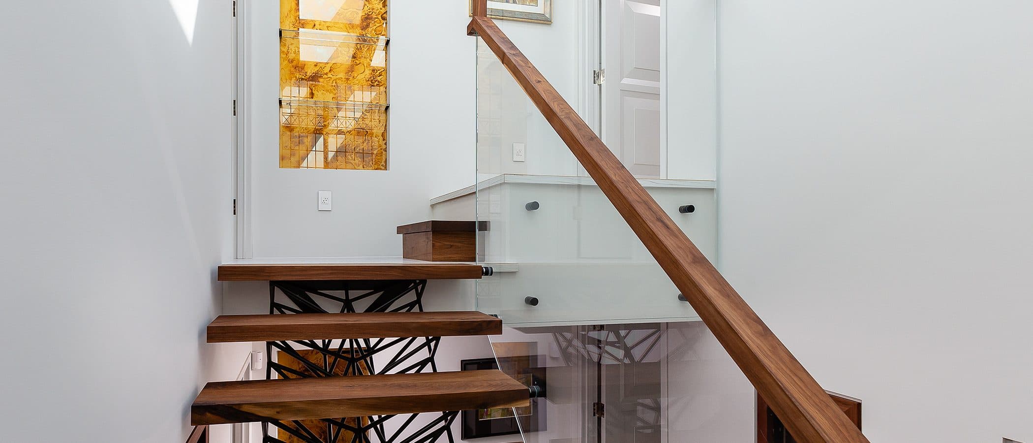 Close view of a black steel lattice grid panel beside a walnut framed skylight window at the stair landing.