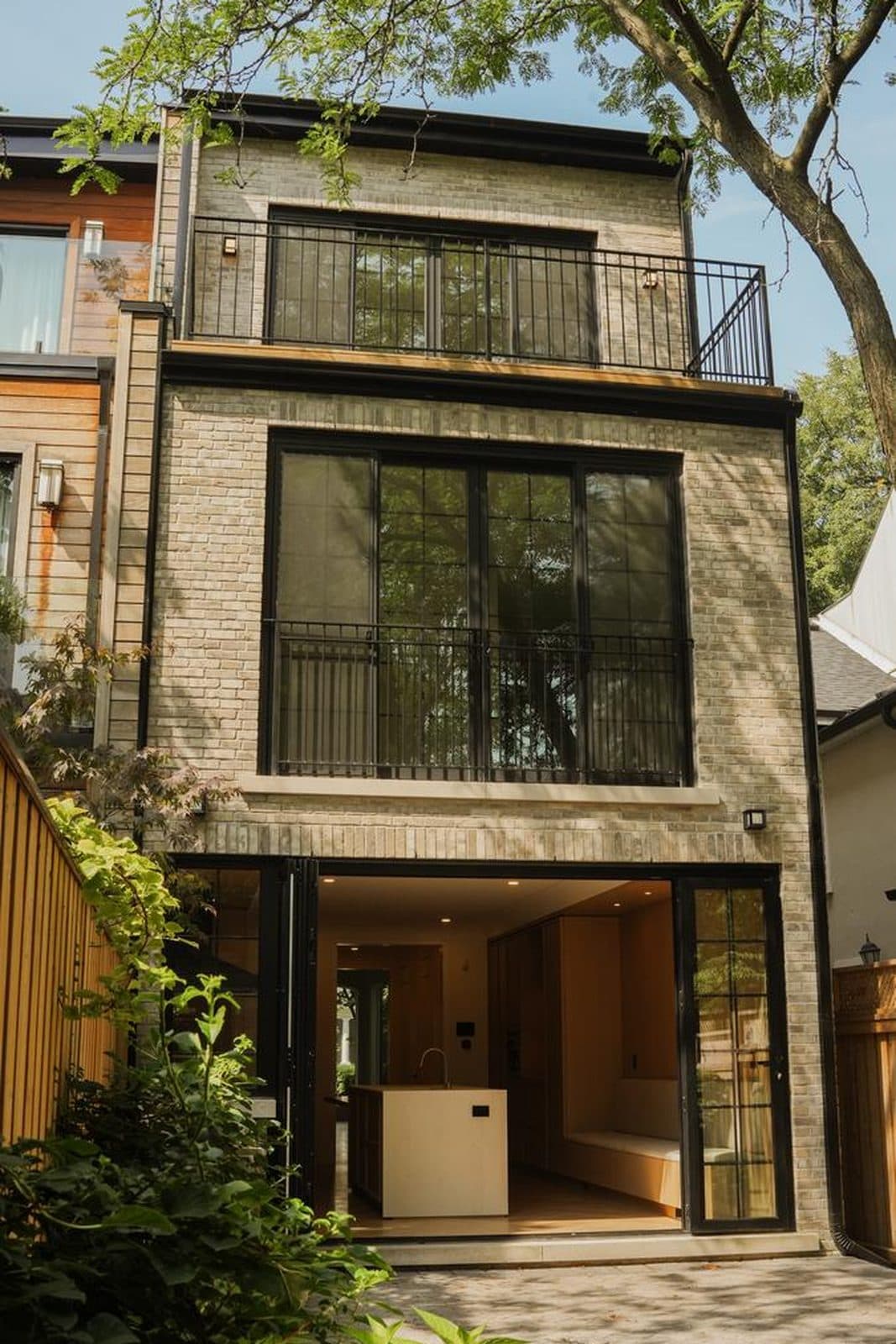 Rear elevation in stacked black steel windows and iron balconies opening to a courtyard