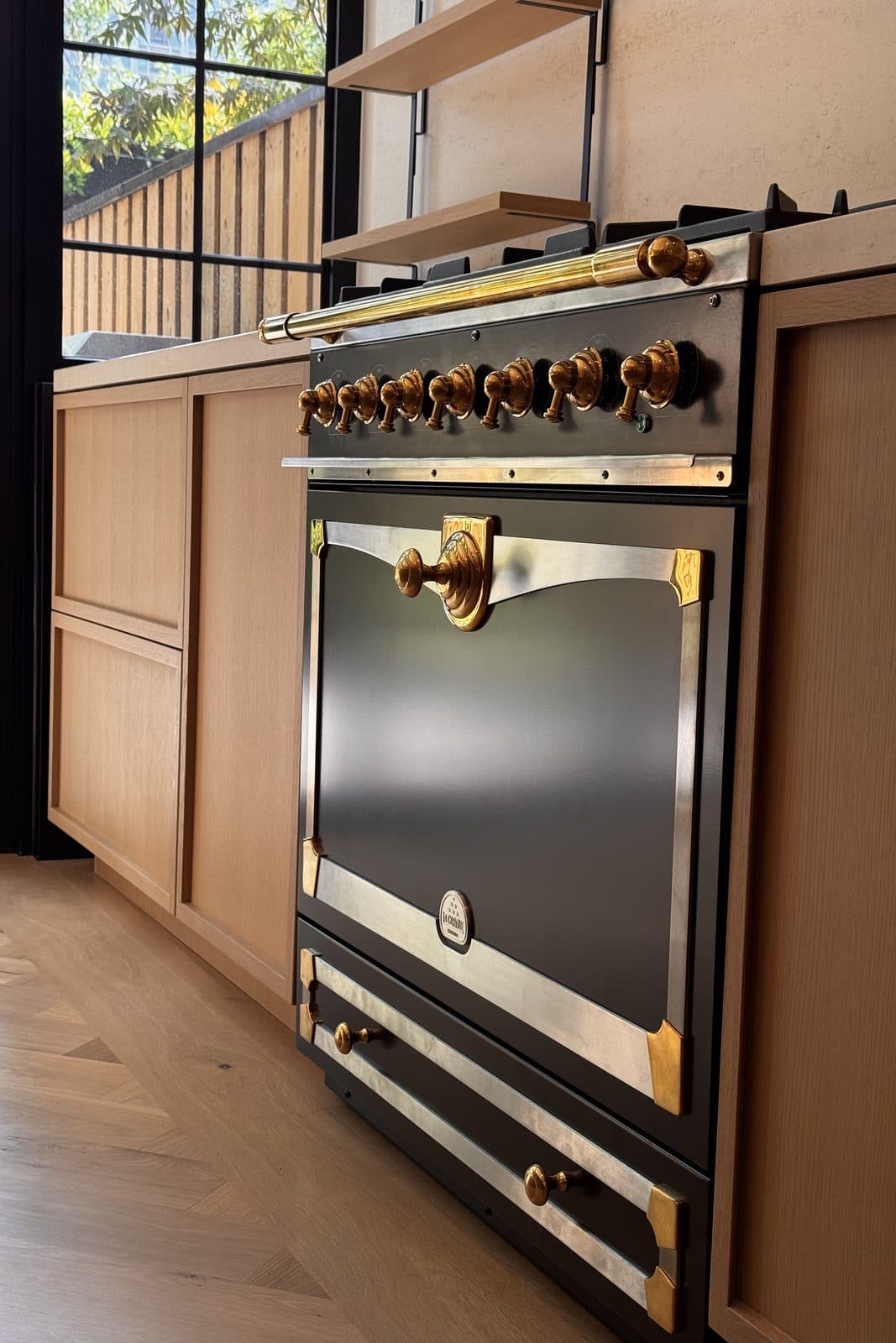 Detail of a dark range with polished brass control knobs