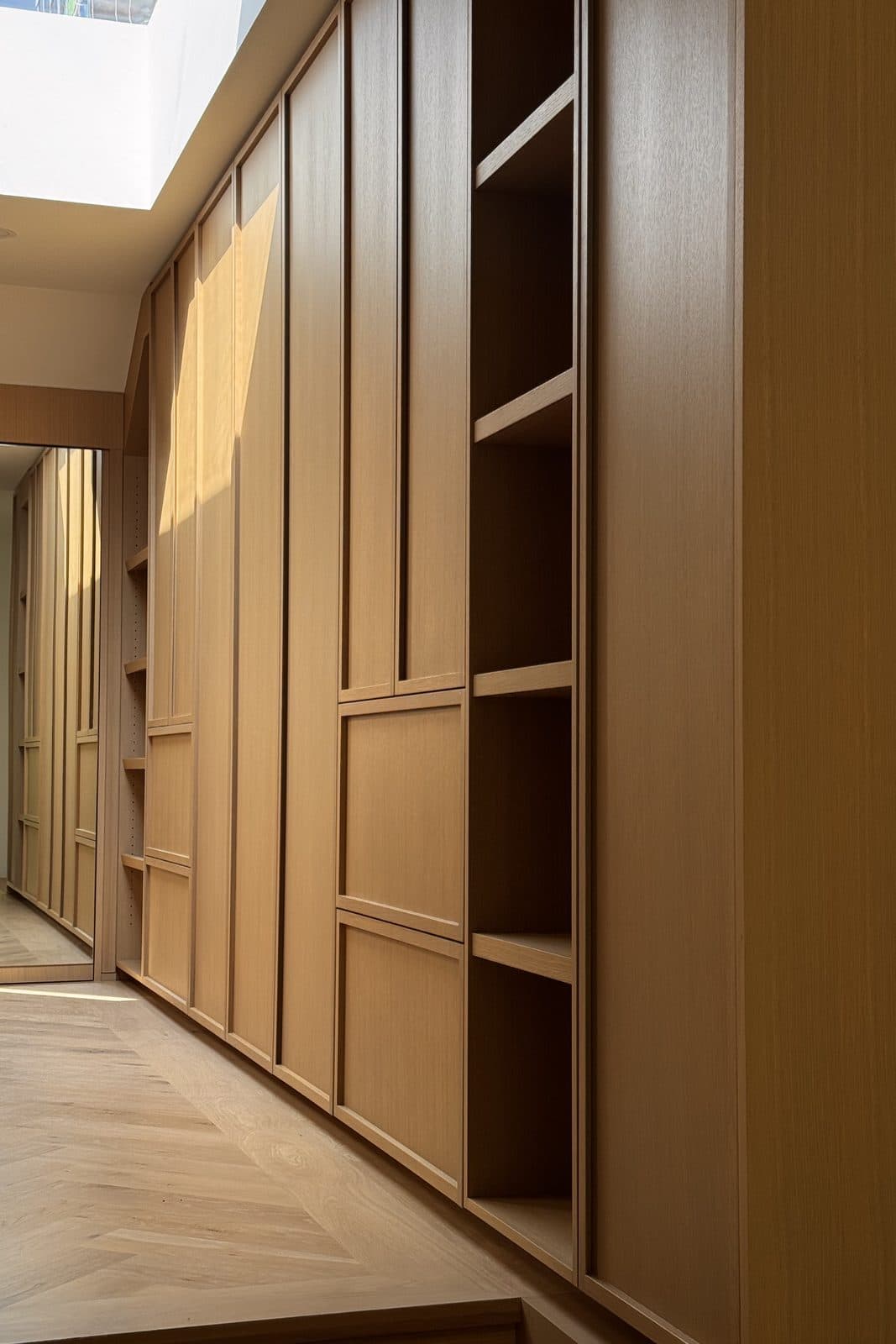 Hallway lined in oak millwork above a herringbone wood floor