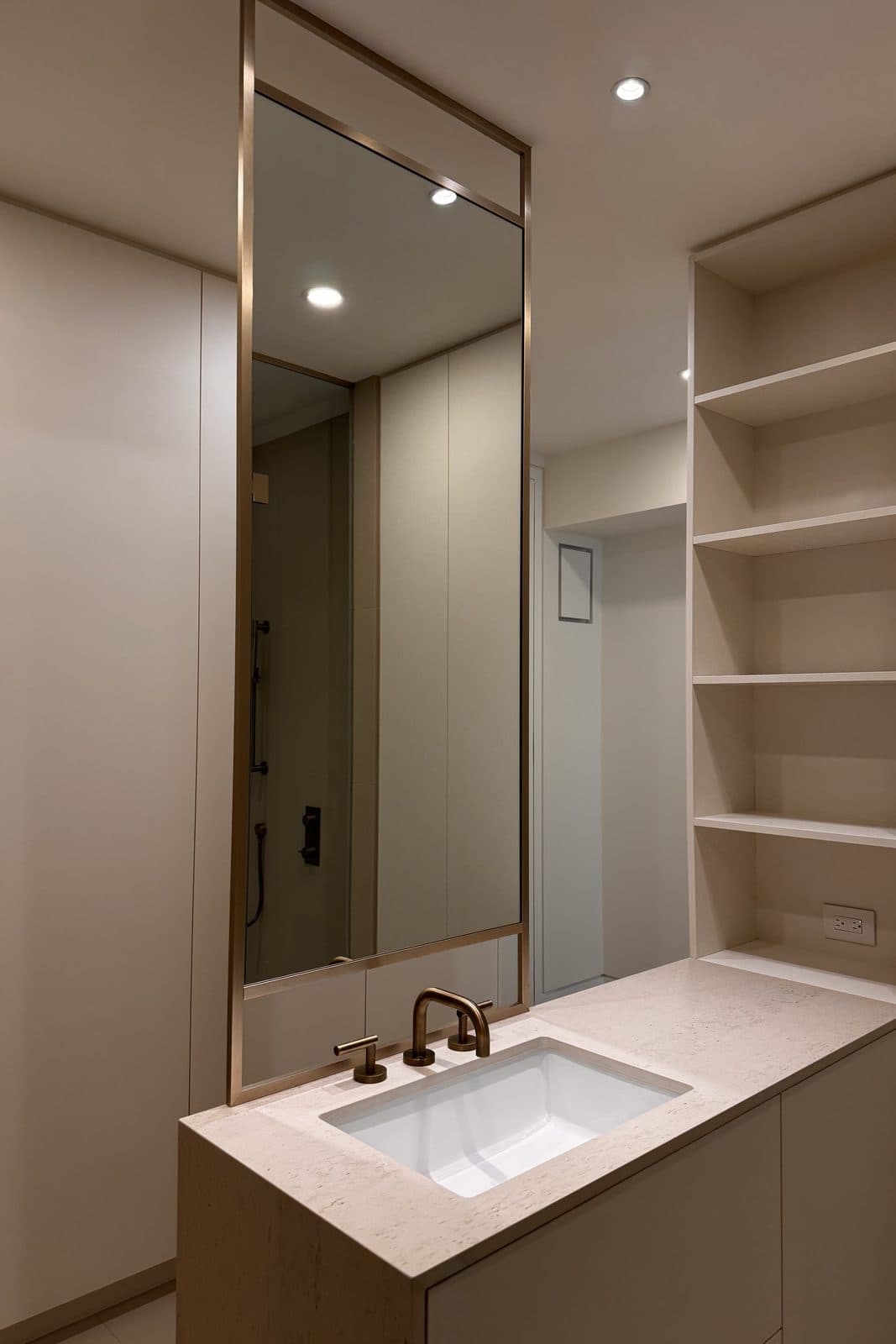 Bathroom vanity in quartz beside a tall mirrored millwork column