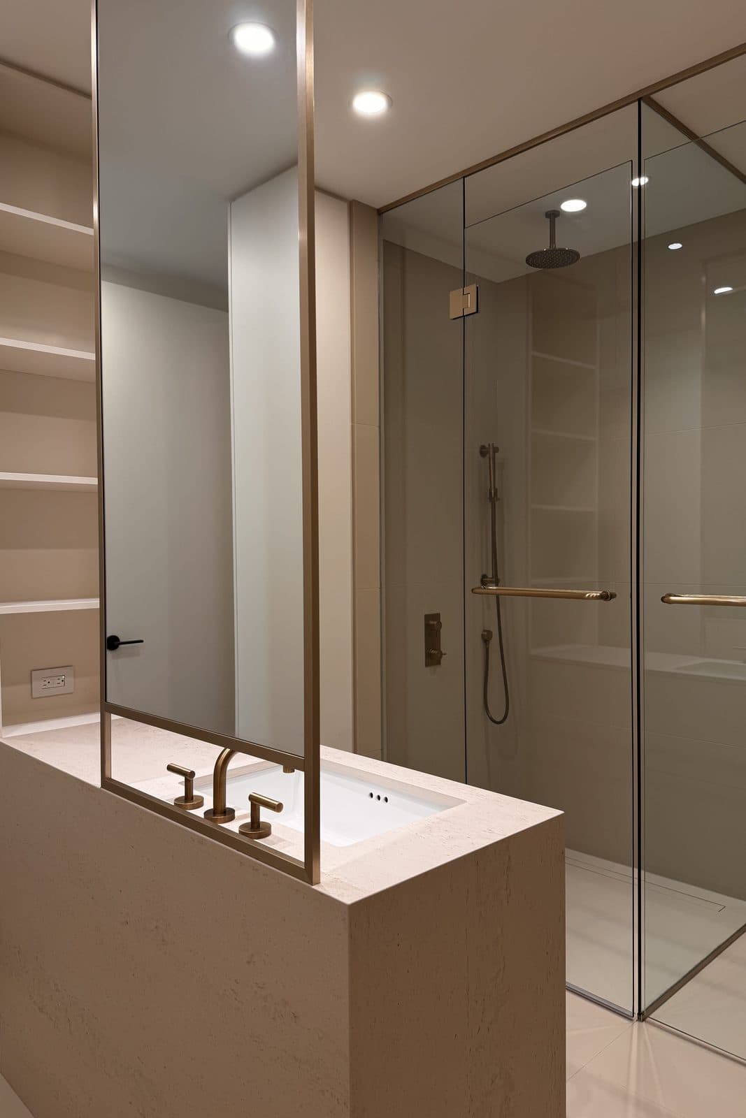Glass-enclosed shower beside open shelving and a stone vanity