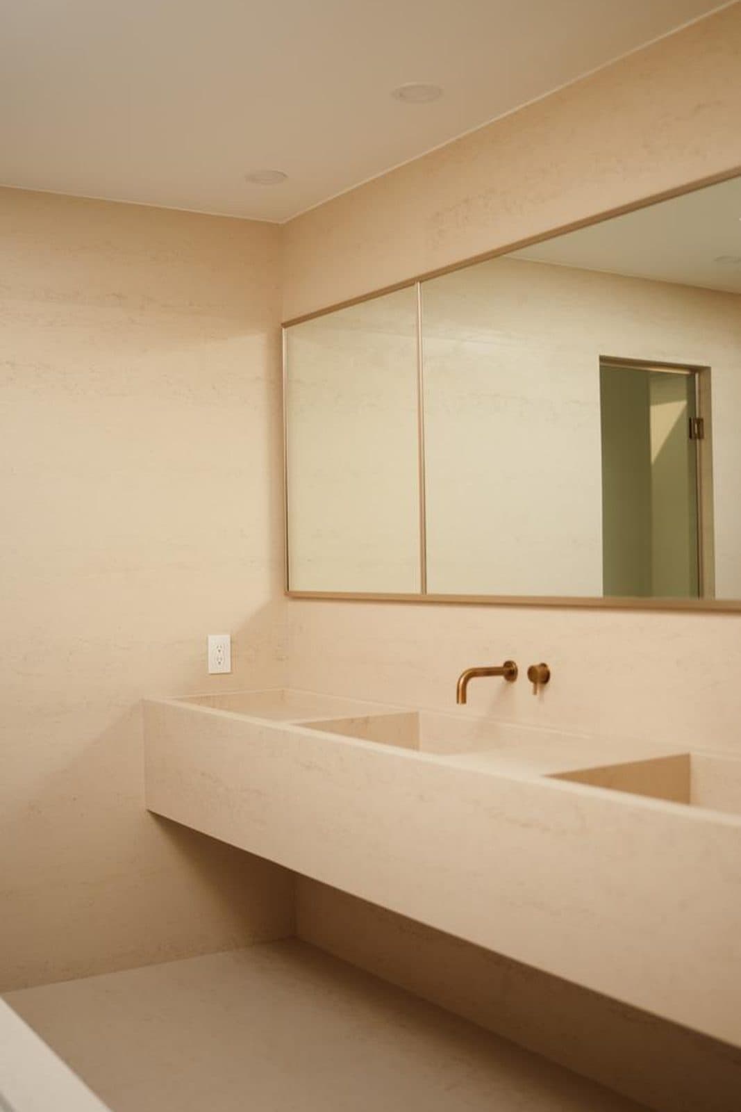 Floating stone double vanity beneath a wall mirror