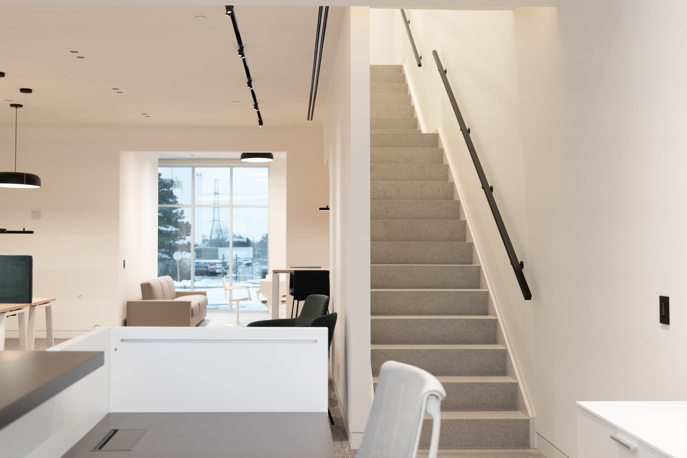 Reception desk in pale millwork beneath a clean ceiling plane with track lighting