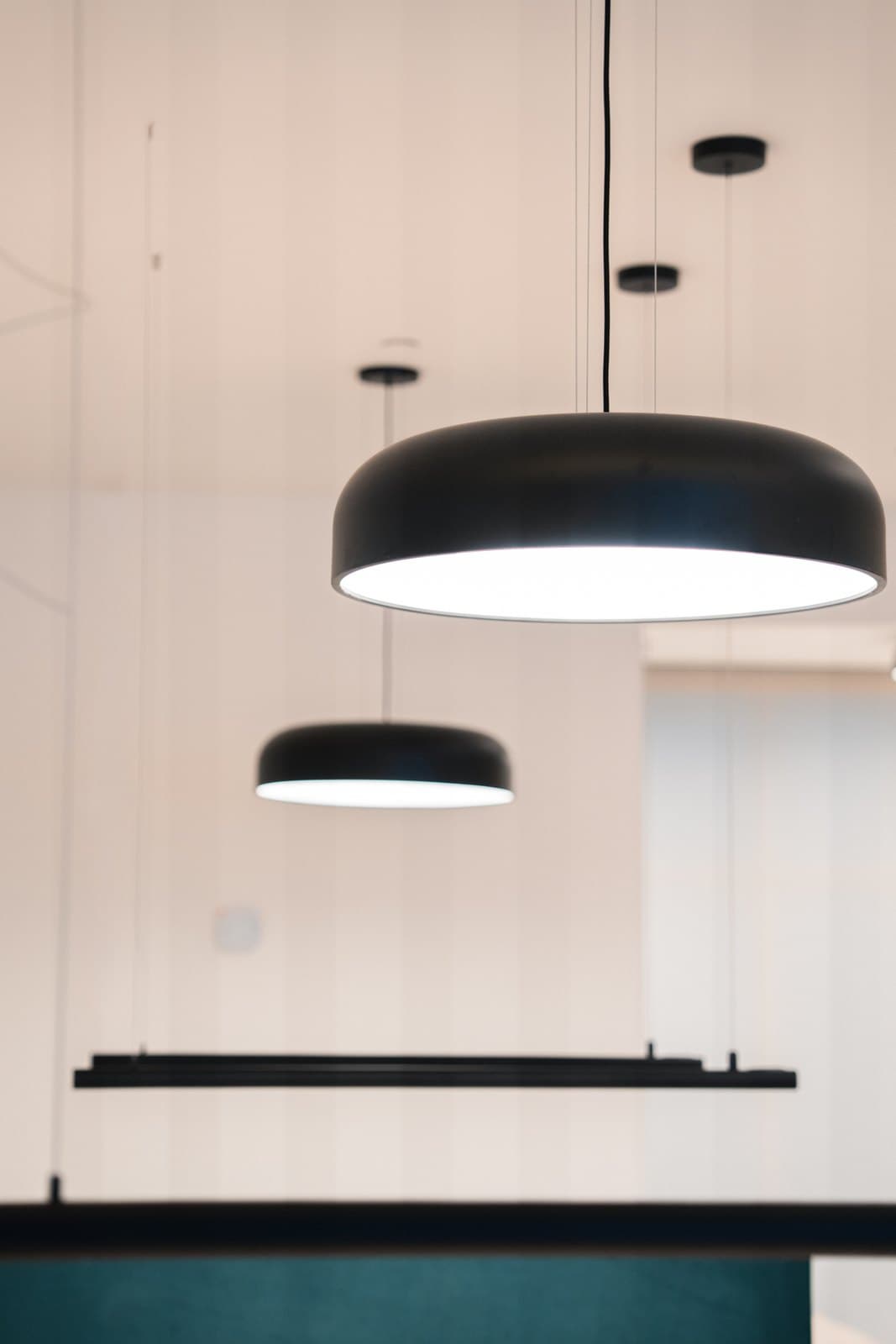 Meeting table lit by a large drum pendant in a calm minimal interior