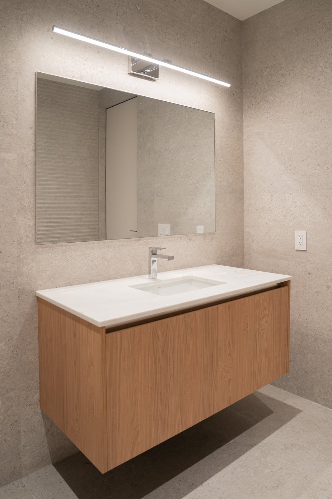 Washroom vanity in oak and stone with a fluted feature wall and a linear mirror