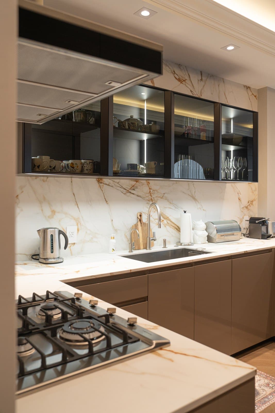 Kitchen in gold veined marble with backlit glass uppers and a gas cooktop