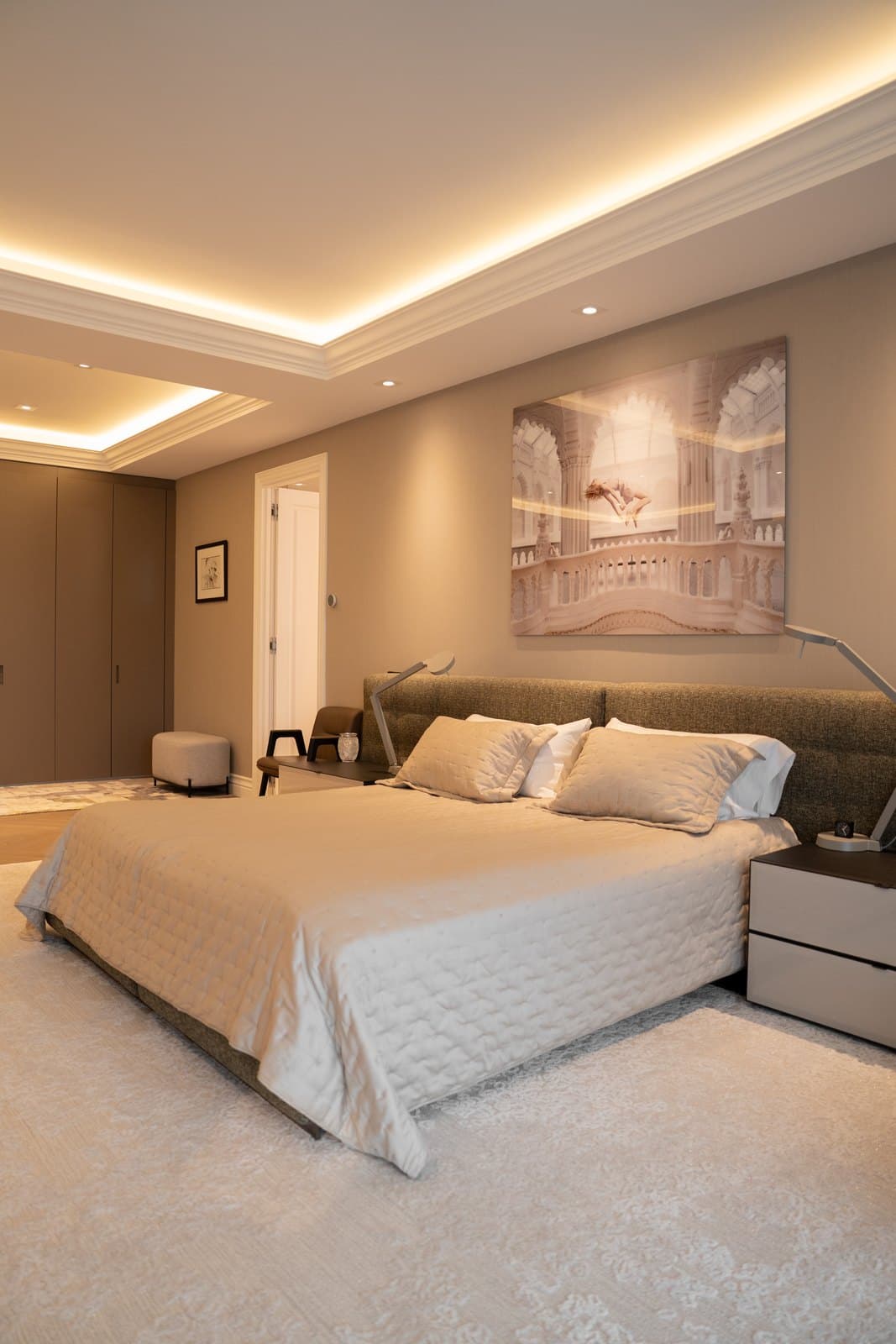 Bedroom finished in soft neutrals with concealed cove lighting