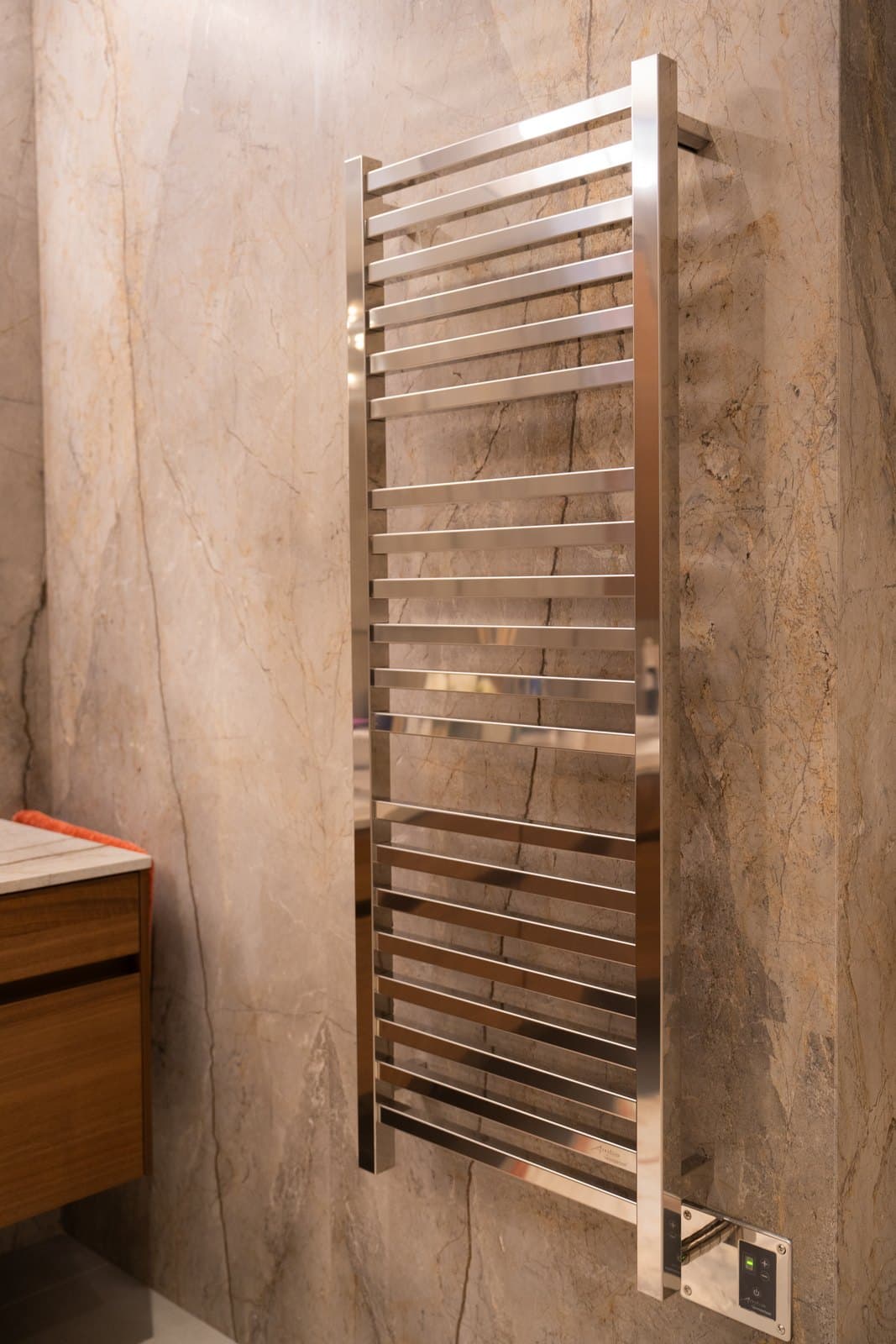 Polished towel warmer against large format stone