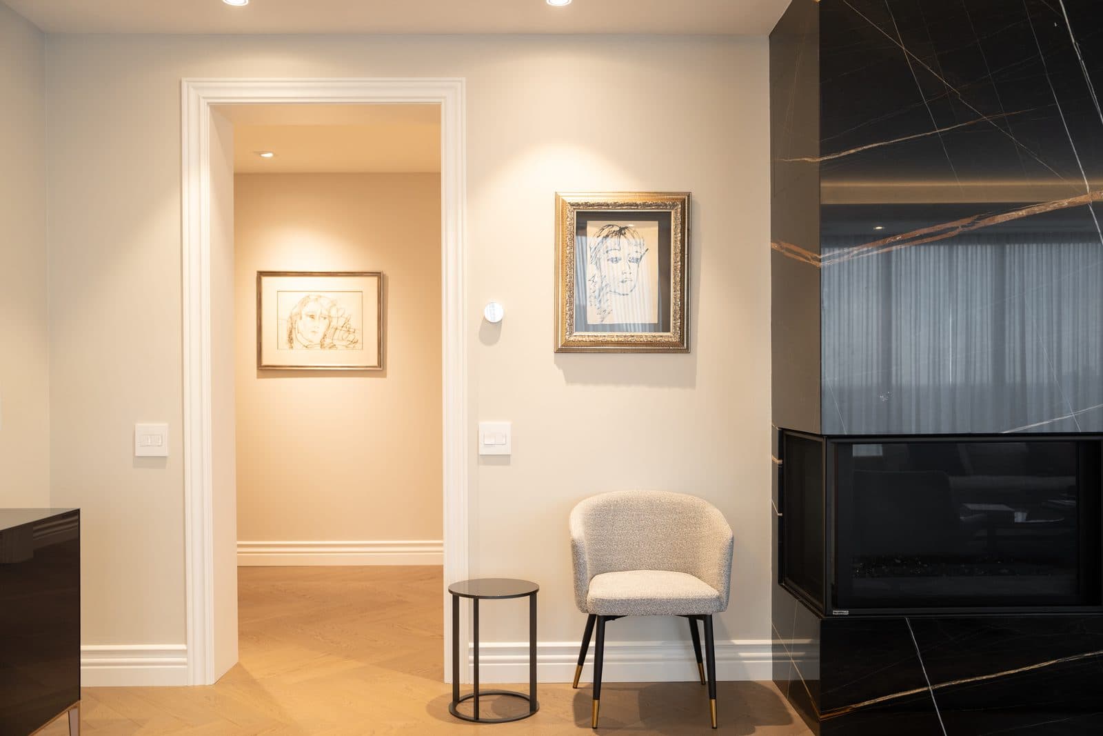 Hallway with sketch portraits in gold frames and a boucle chair
