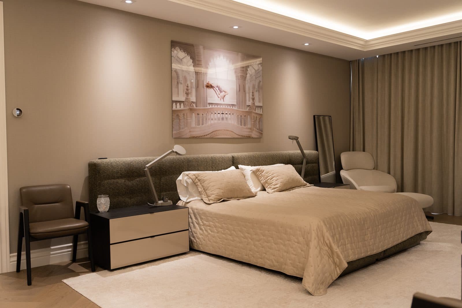 Bedroom with a tufted headboard, framed artwork and a curtained corner
