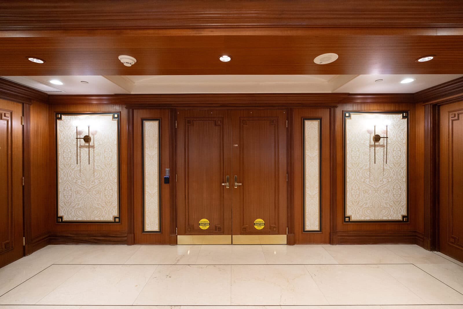 Mahogany elevator lobby with panelled doors and wall sconces