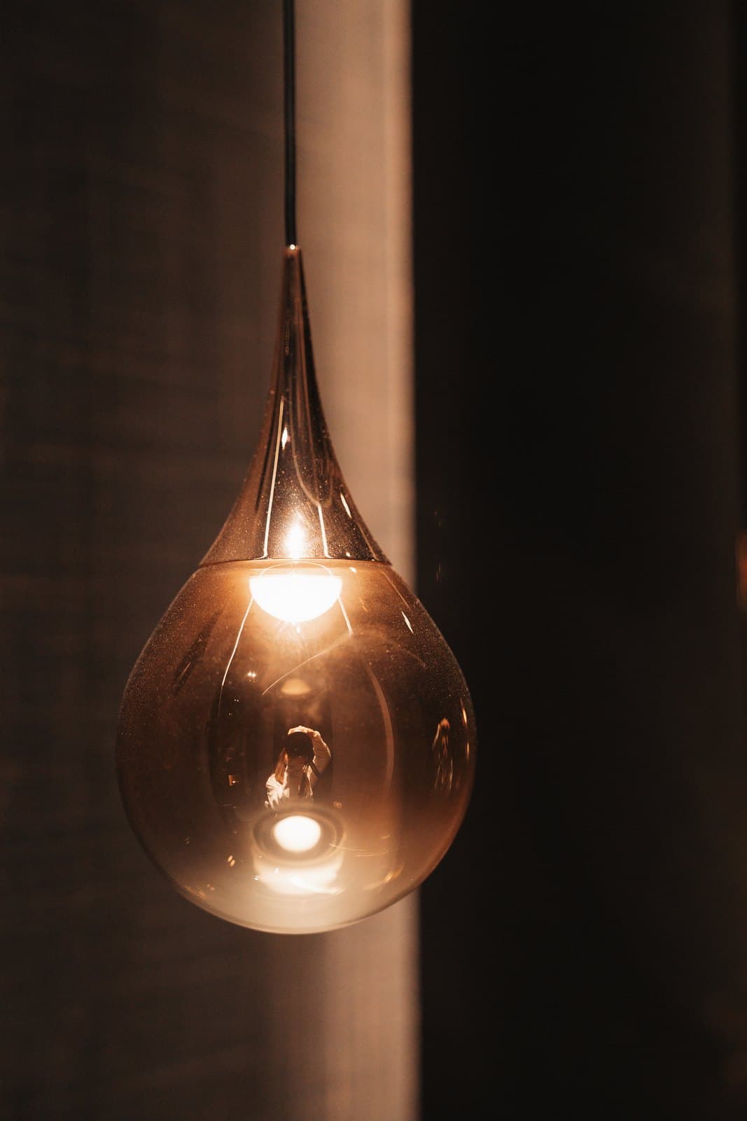 Sculptural pendant light suspended in a dark double height stairwell