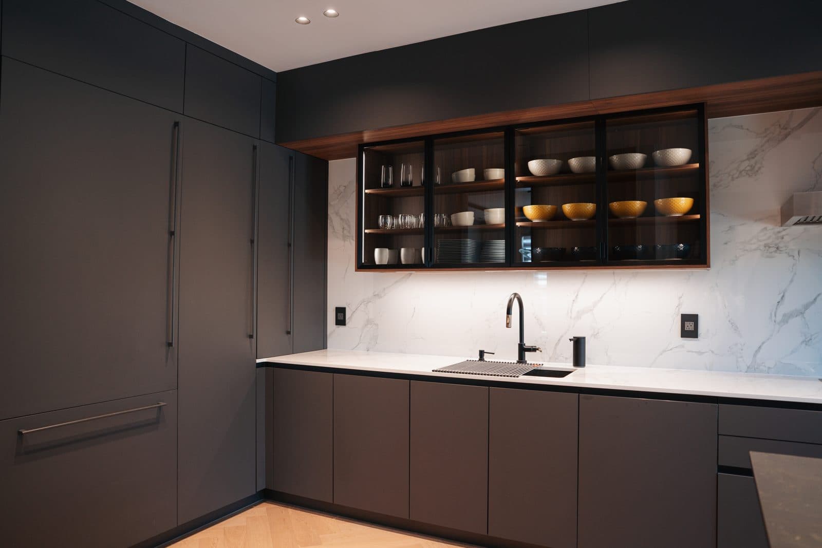 Charcoal kitchen with backlit glass cabinets and a marble backsplash