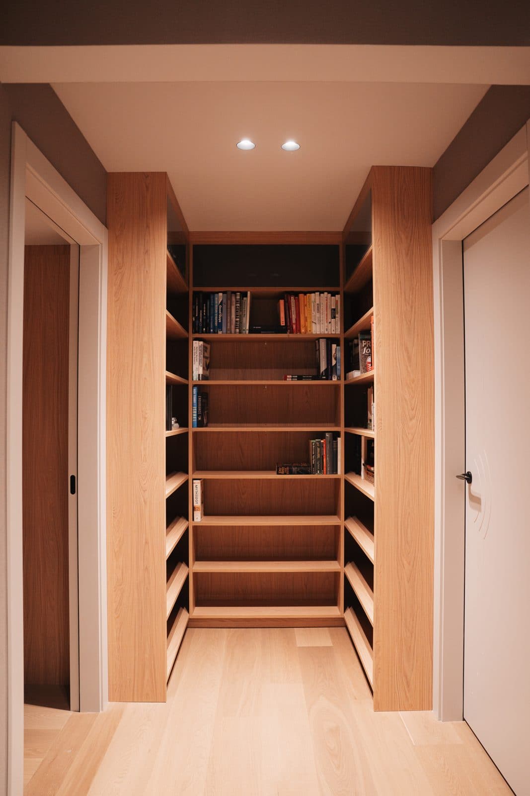 Walnut library corridor with backlit shelving and oak floors