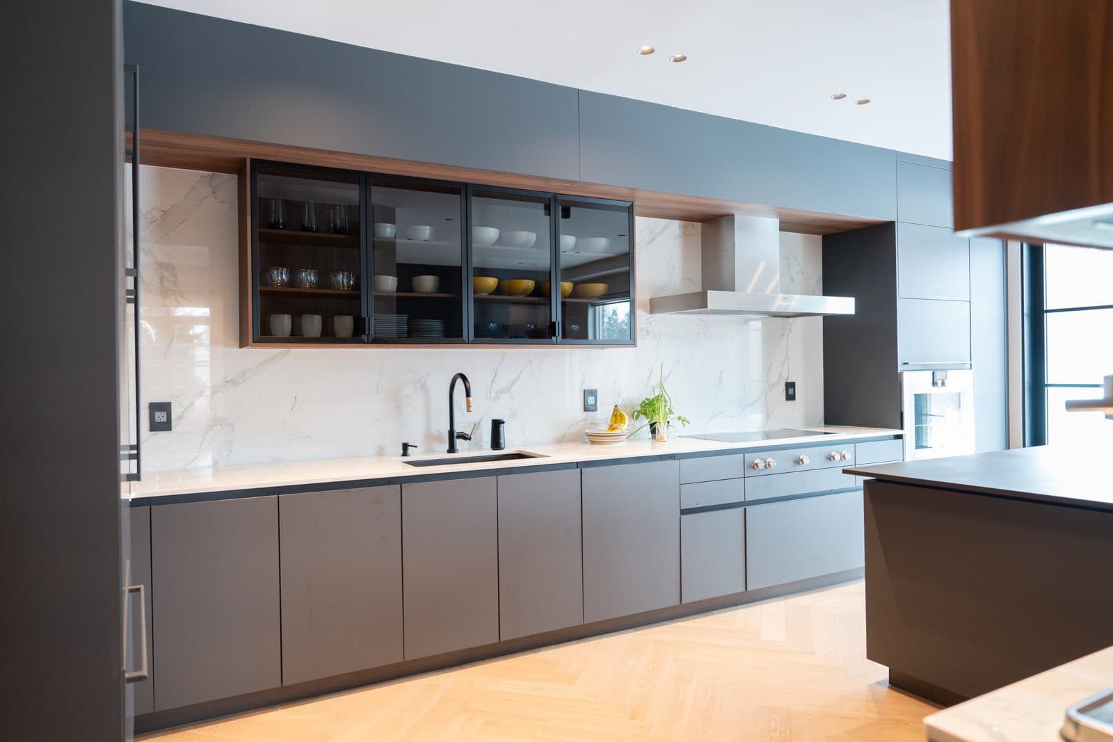 Charcoal kitchen along a marble backsplash with an integrated hood and island