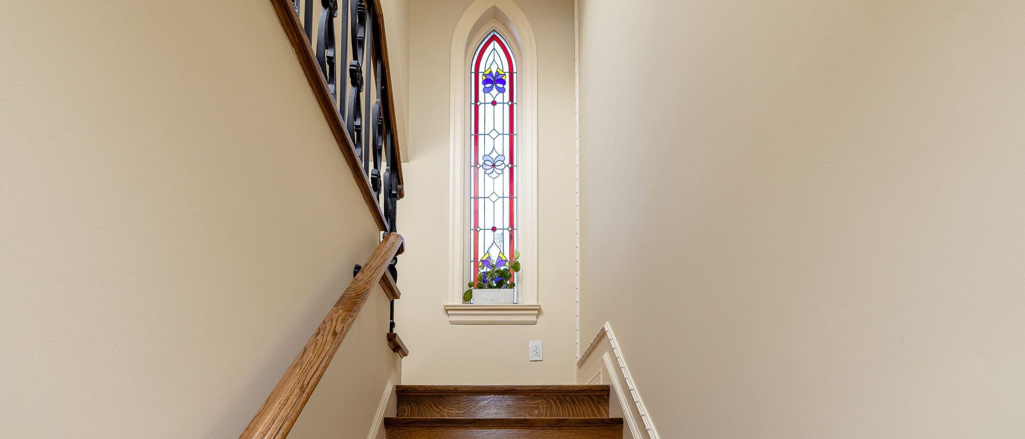Stairwell illuminated by a tall stained glass window in a heritage renovation