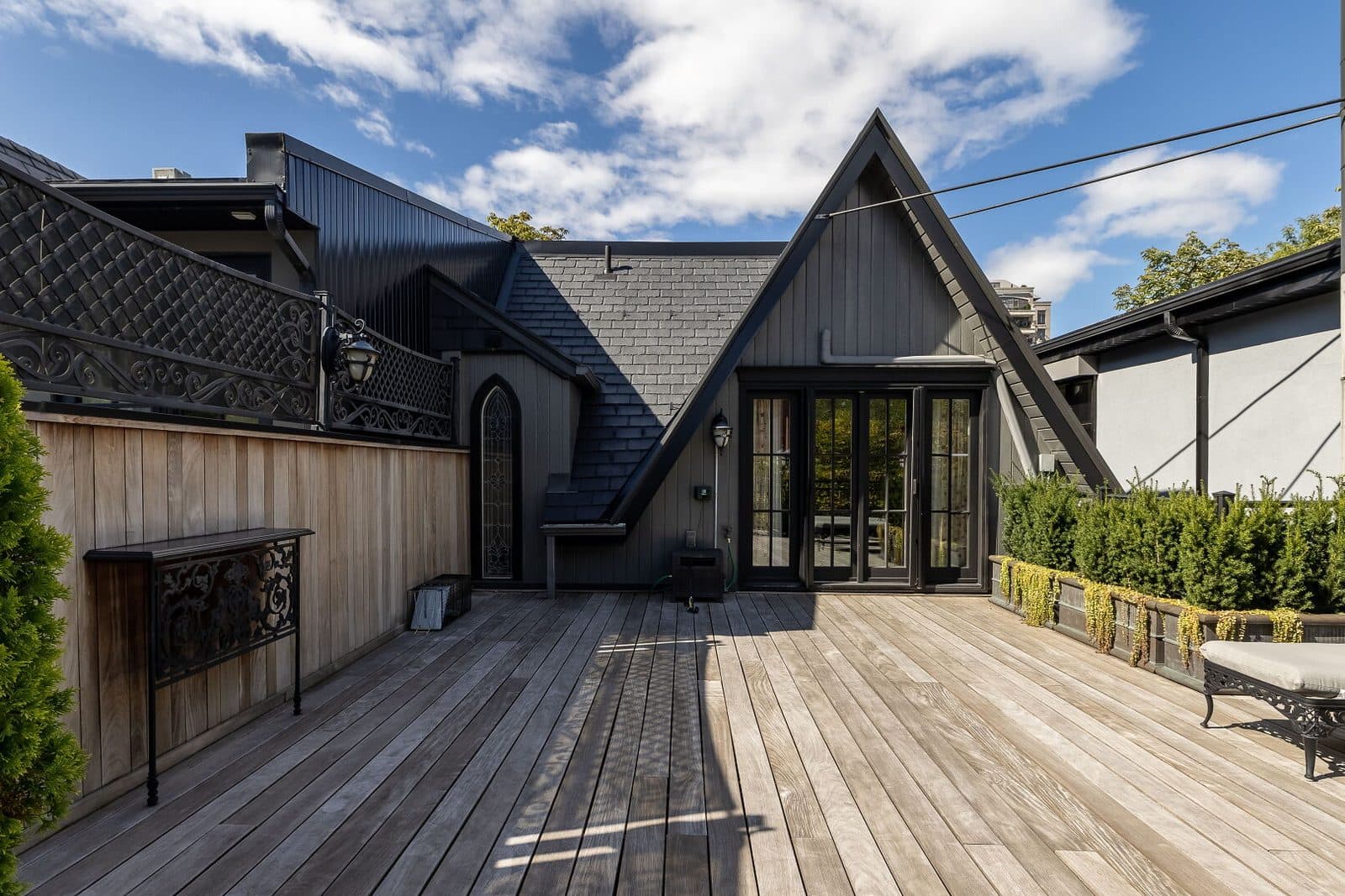 Rear addition in black with iron balconies above a walled garden