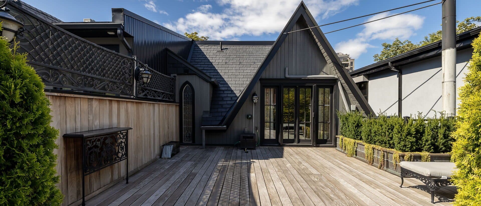 Rear addition in black with iron balconies above a walled garden