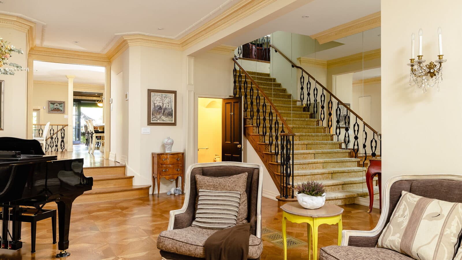 Living room looking toward the main staircase past a mirrored wall and a grand piano