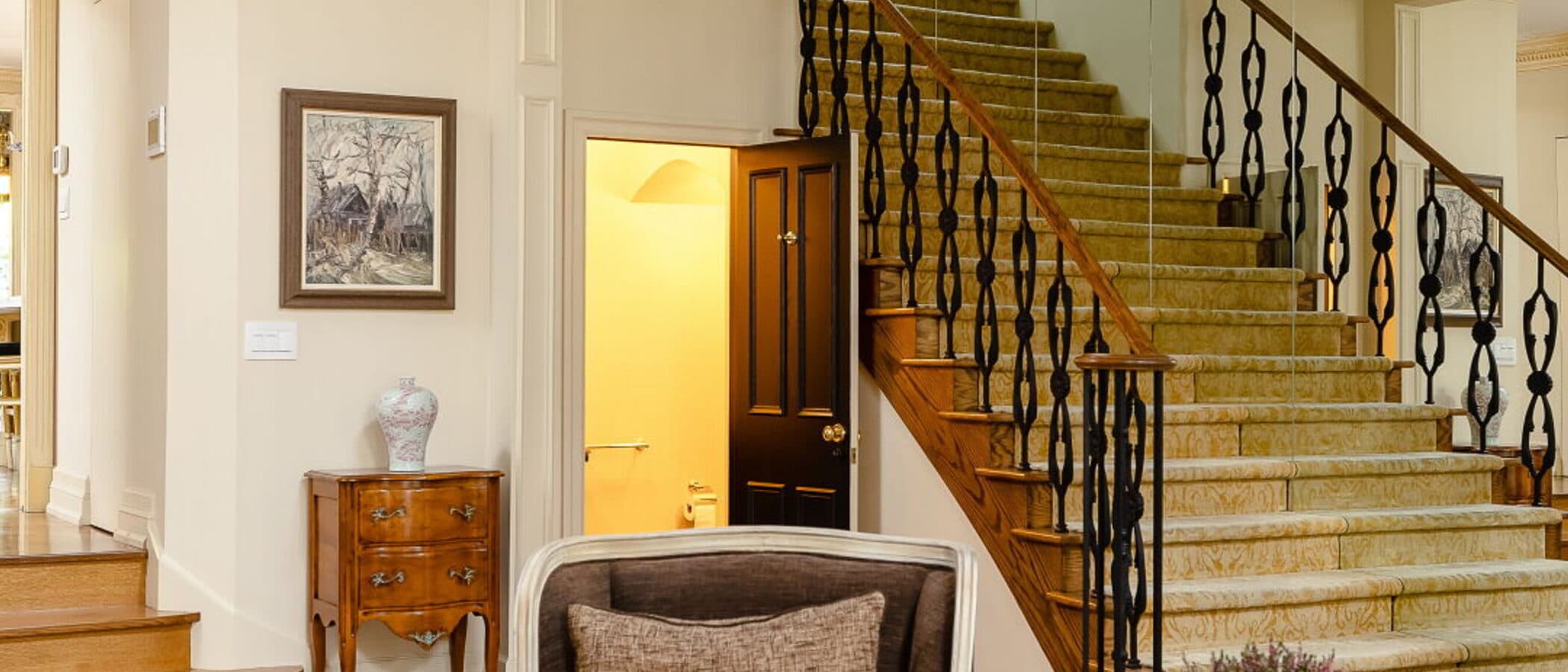 Living room looking toward the main staircase past a mirrored wall and a grand piano