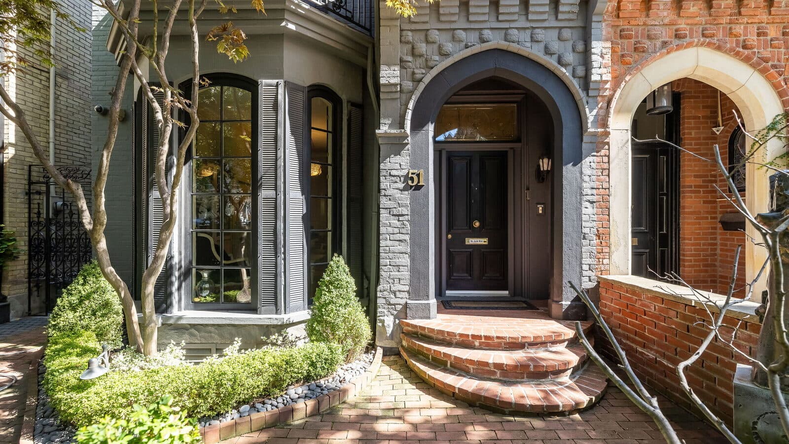 Arched stone and brick entry with a black front door