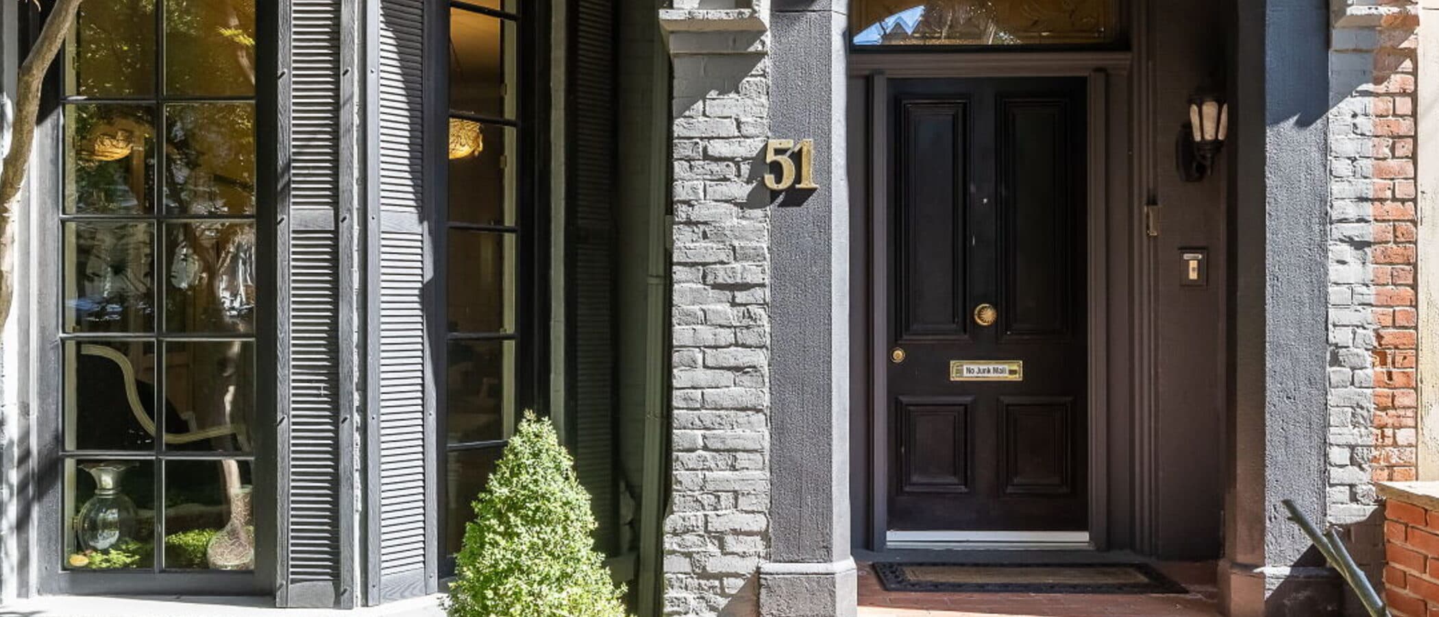 Arched stone and brick entry with a black front door