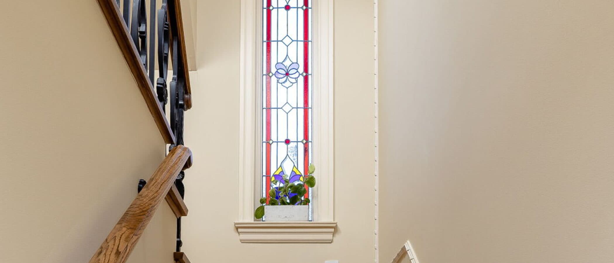 Stairwell illuminated by a tall stained glass window