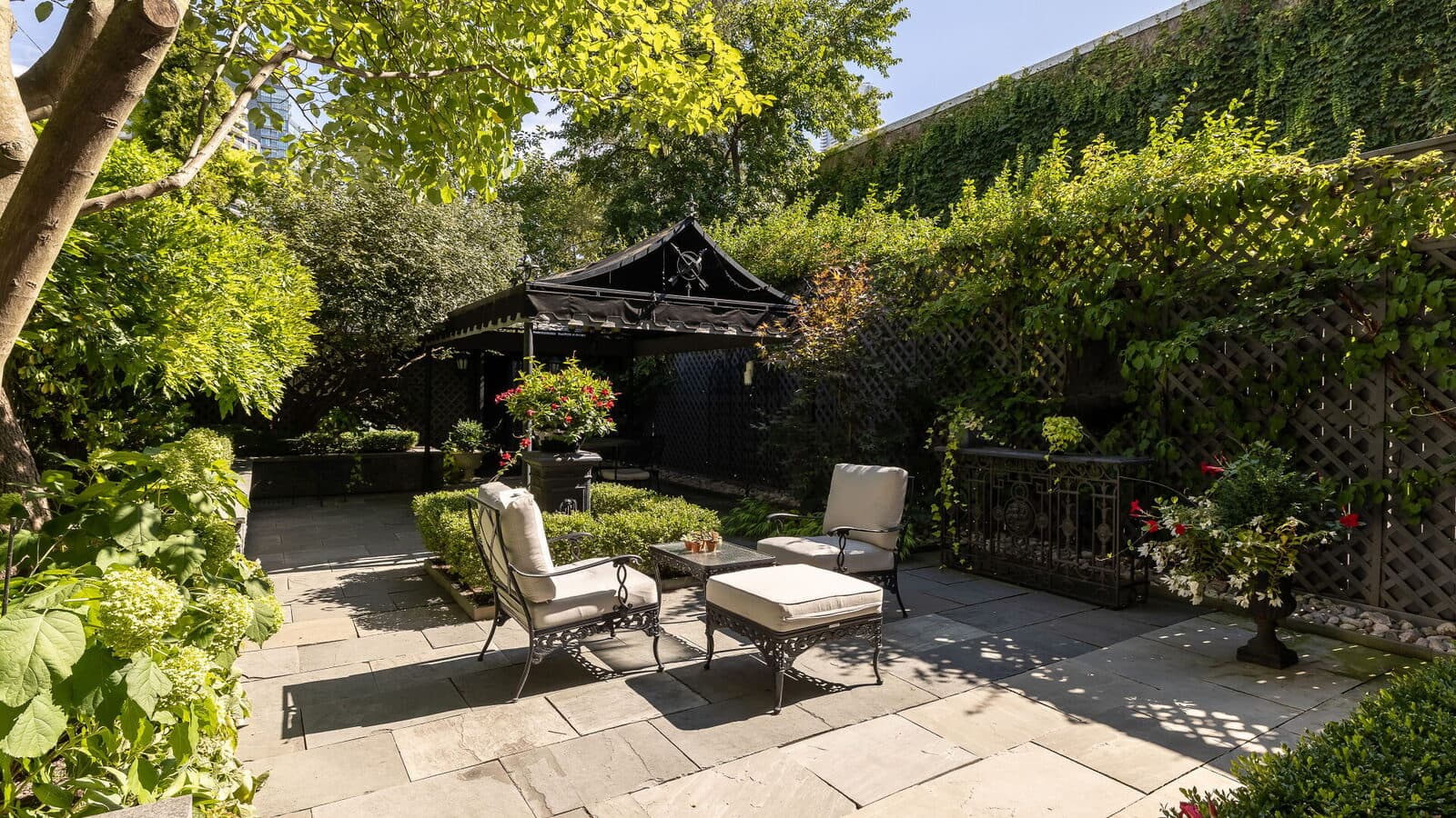 Walled garden courtyard with mature planting and a covered terrace