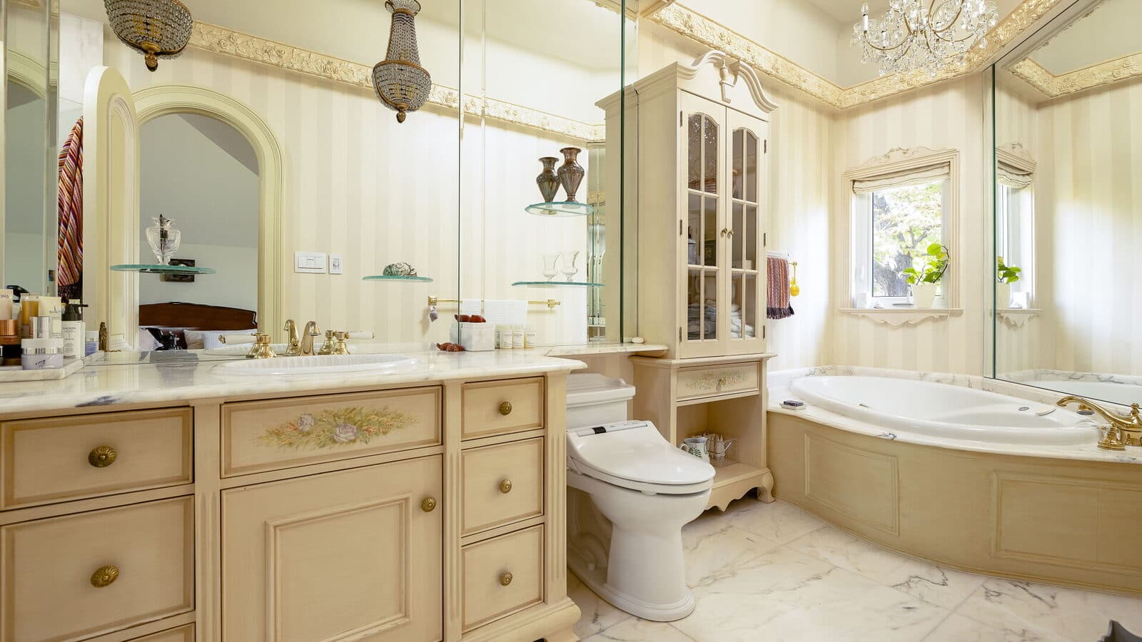 Ensuite bath with an arched mirror, a garden window and a chandelier