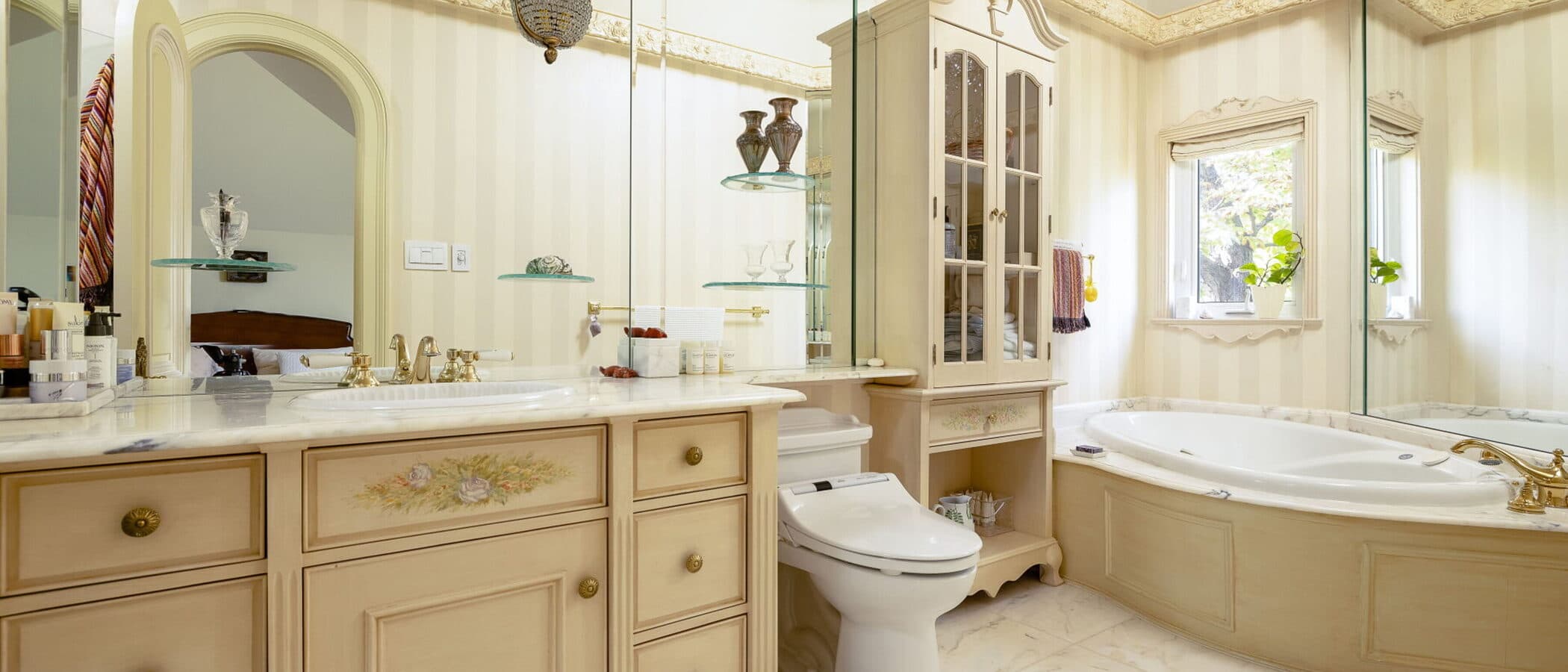 Ensuite bath with an arched mirror, a garden window and a chandelier