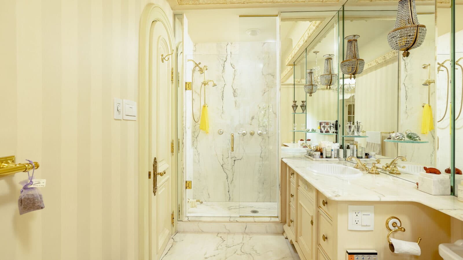 Marble shower and mirrored vanity with crystal sconces