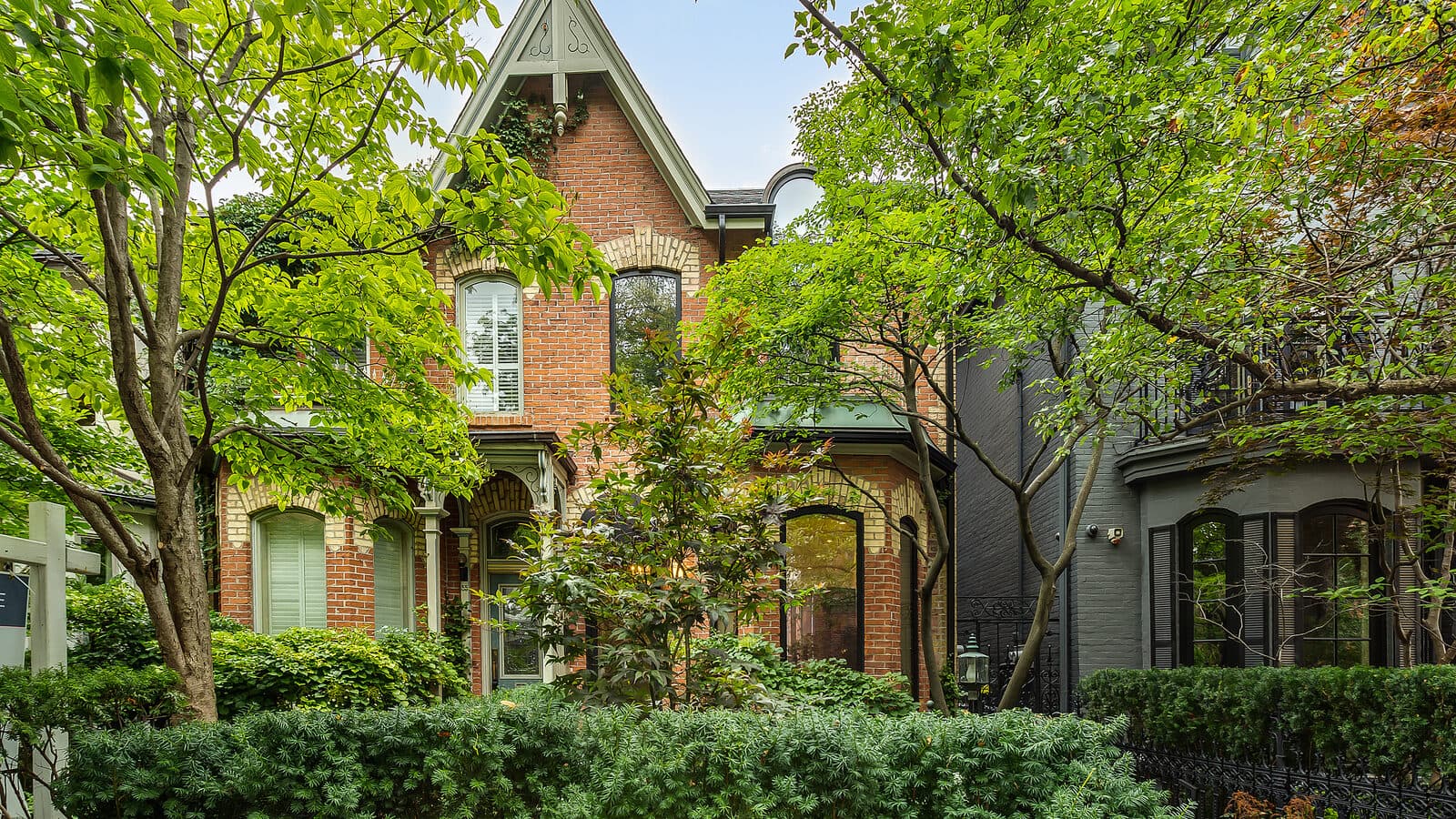 Red brick heritage facade shaded by mature trees