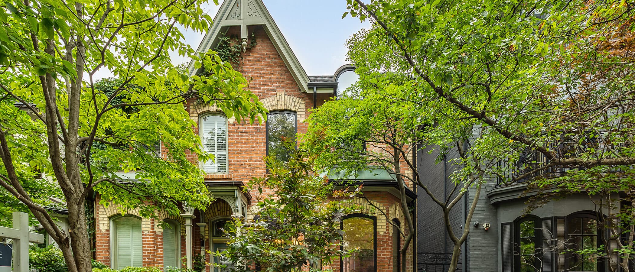 Two storey red brick Victorian facade with cream brick banding and black framed windows
