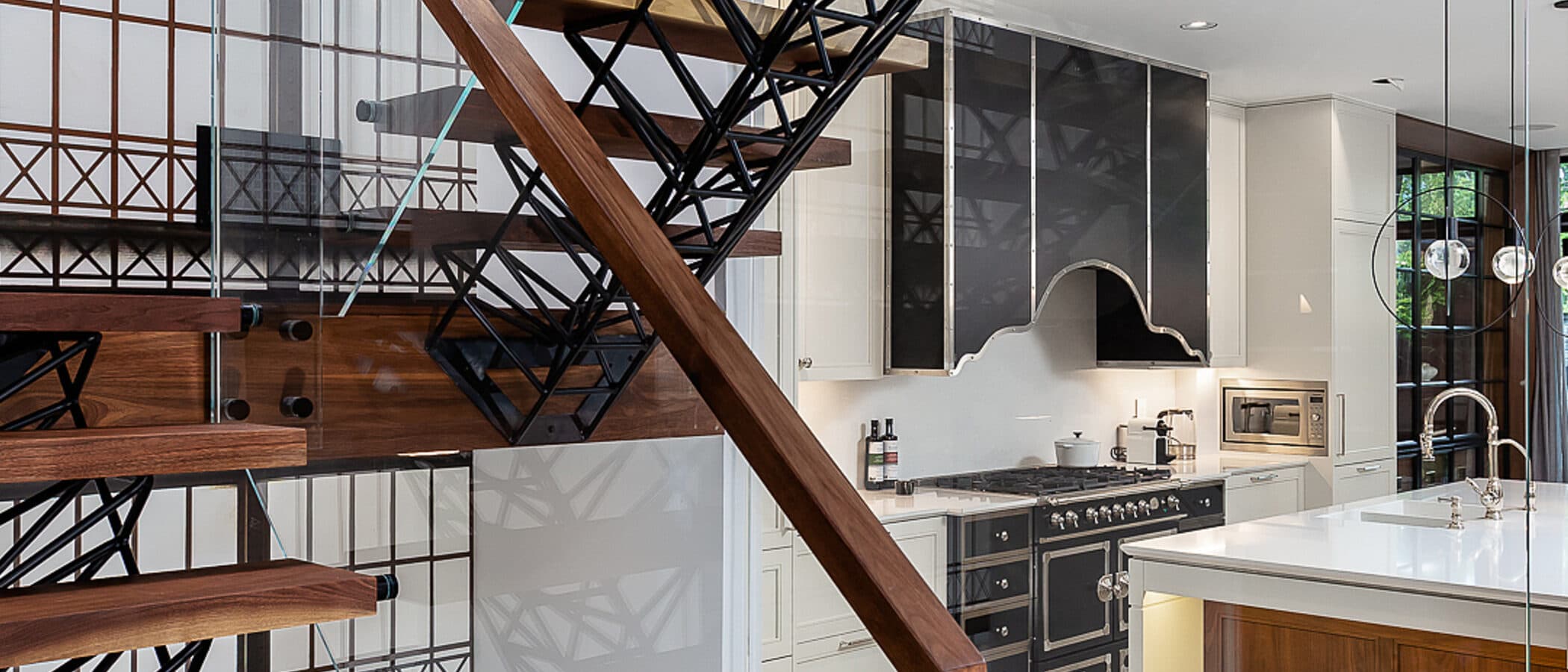 Spiral stair beside a glazed wall with a large station clock and the kitchen beyond