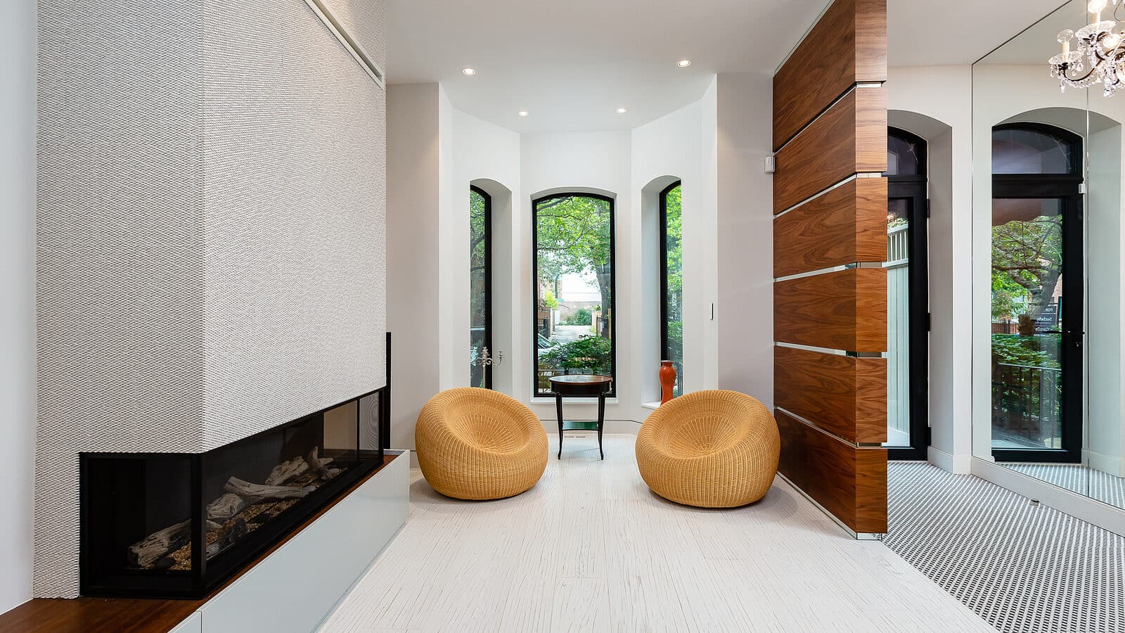 Living room fireplace with wicker poufs and arched windows to the street