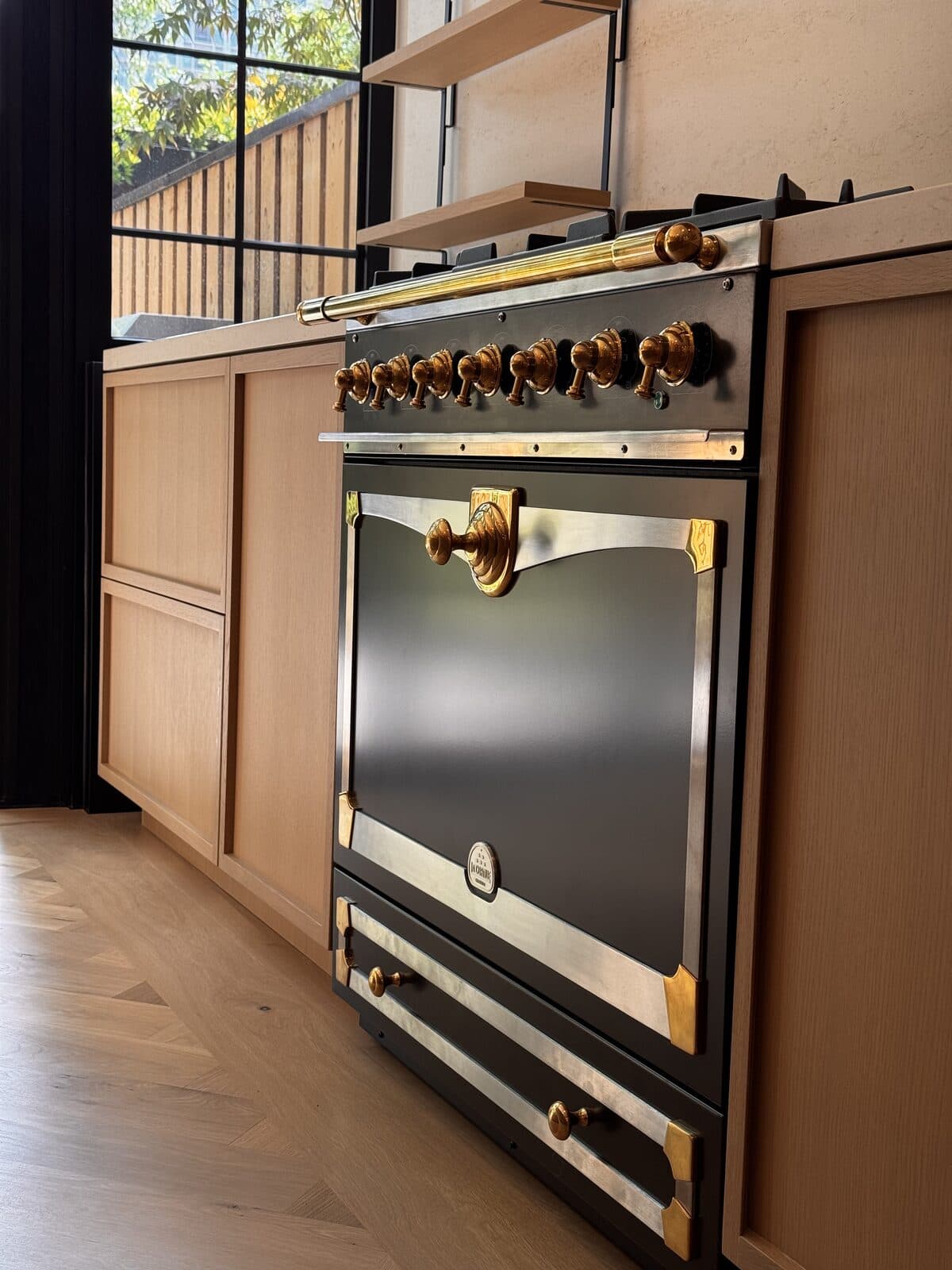 Detail of a dark range with polished brass control knobs
