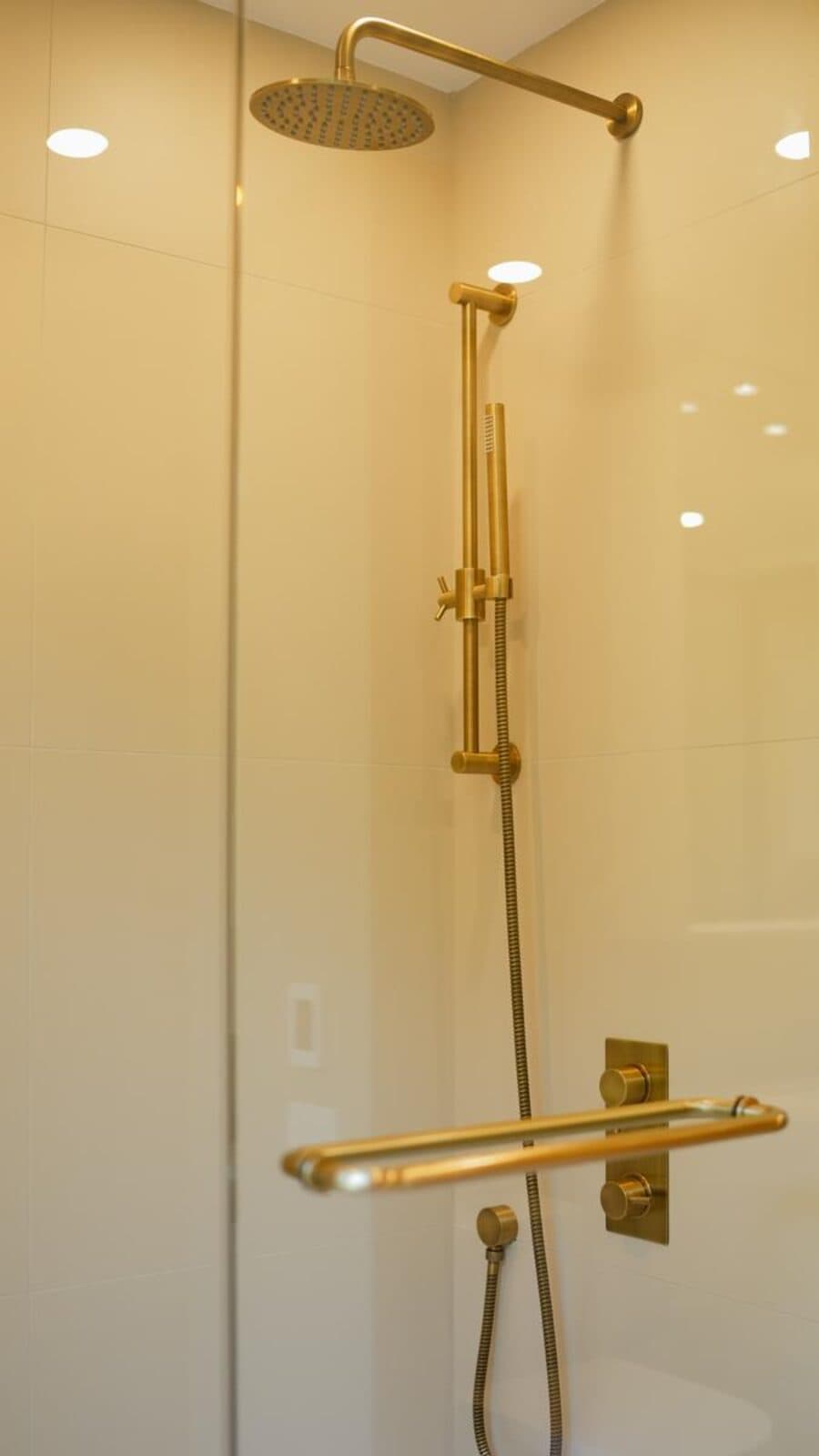 Detail of a brass shower valve set against frameless glass