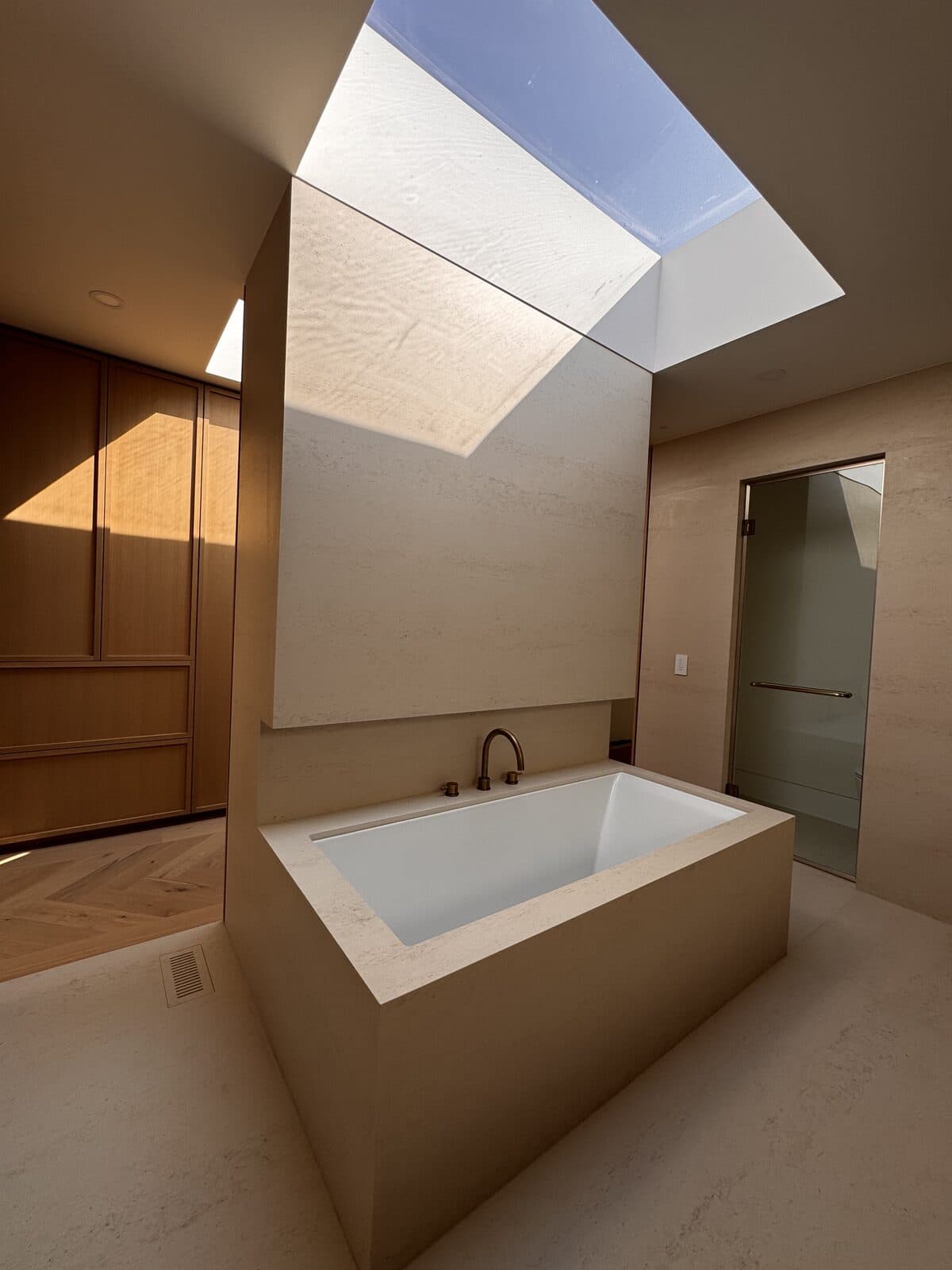 Freestanding soaking tub beneath a skylight in an oak lined bathroom