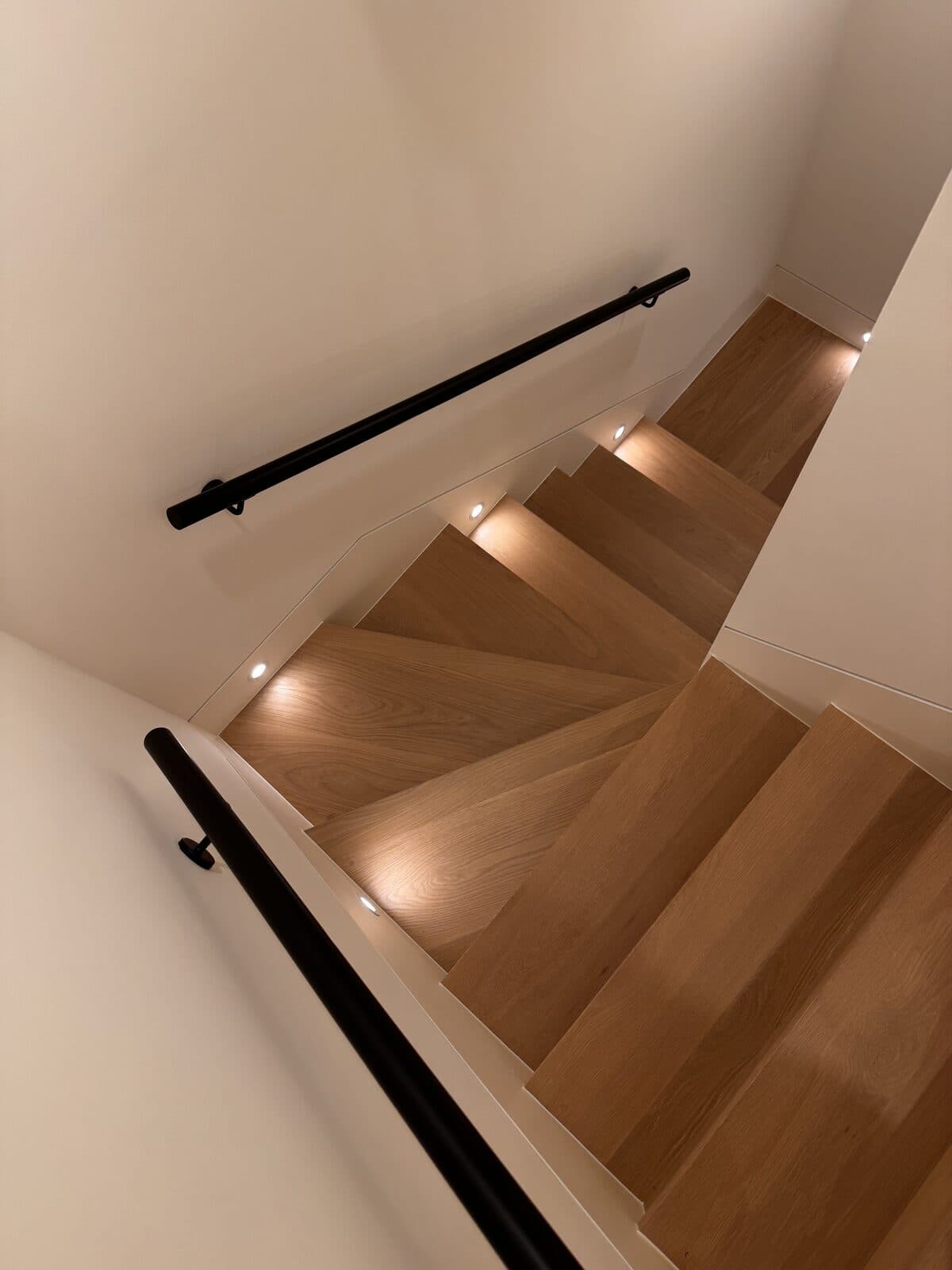 Overhead view of an oak staircase with a black steel handrail