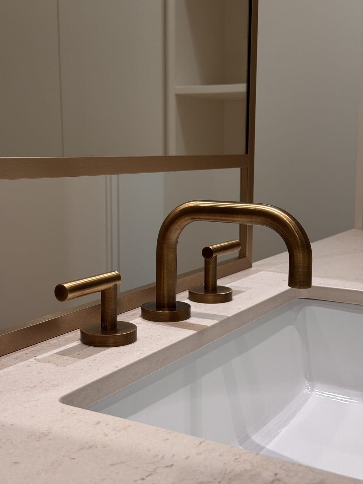 Detail of a wall mounted brass faucet over a stone sink