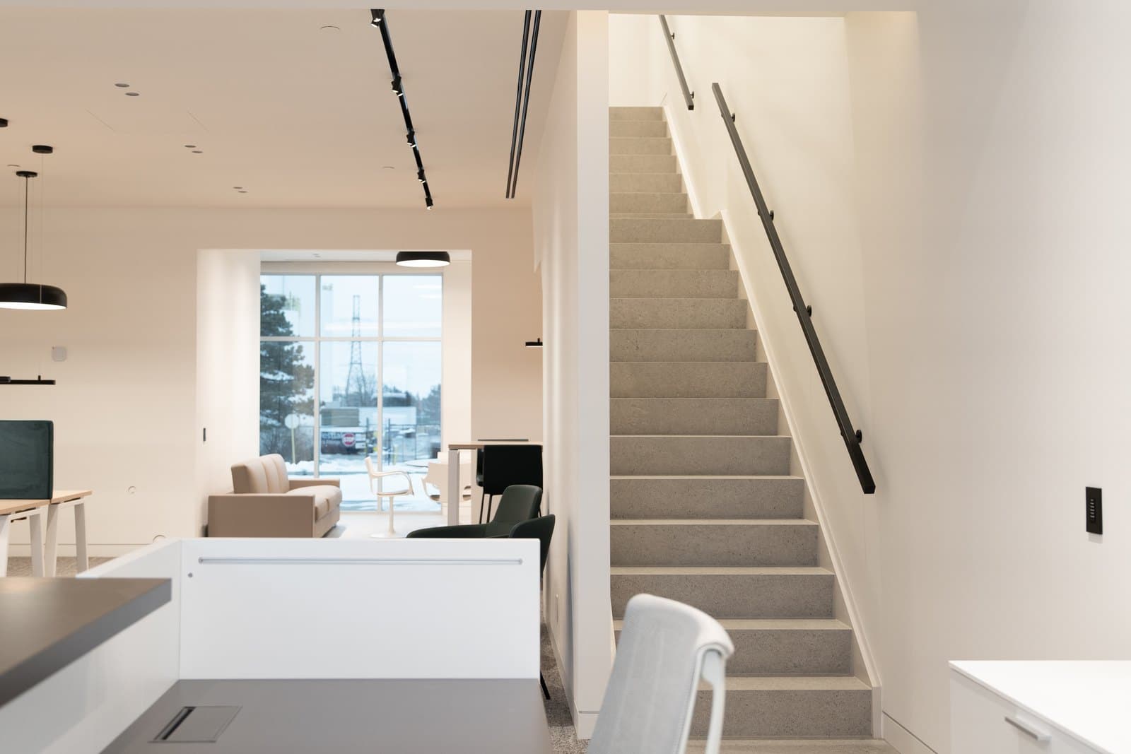 Reception desk in pale millwork beneath a clean ceiling plane with track lighting