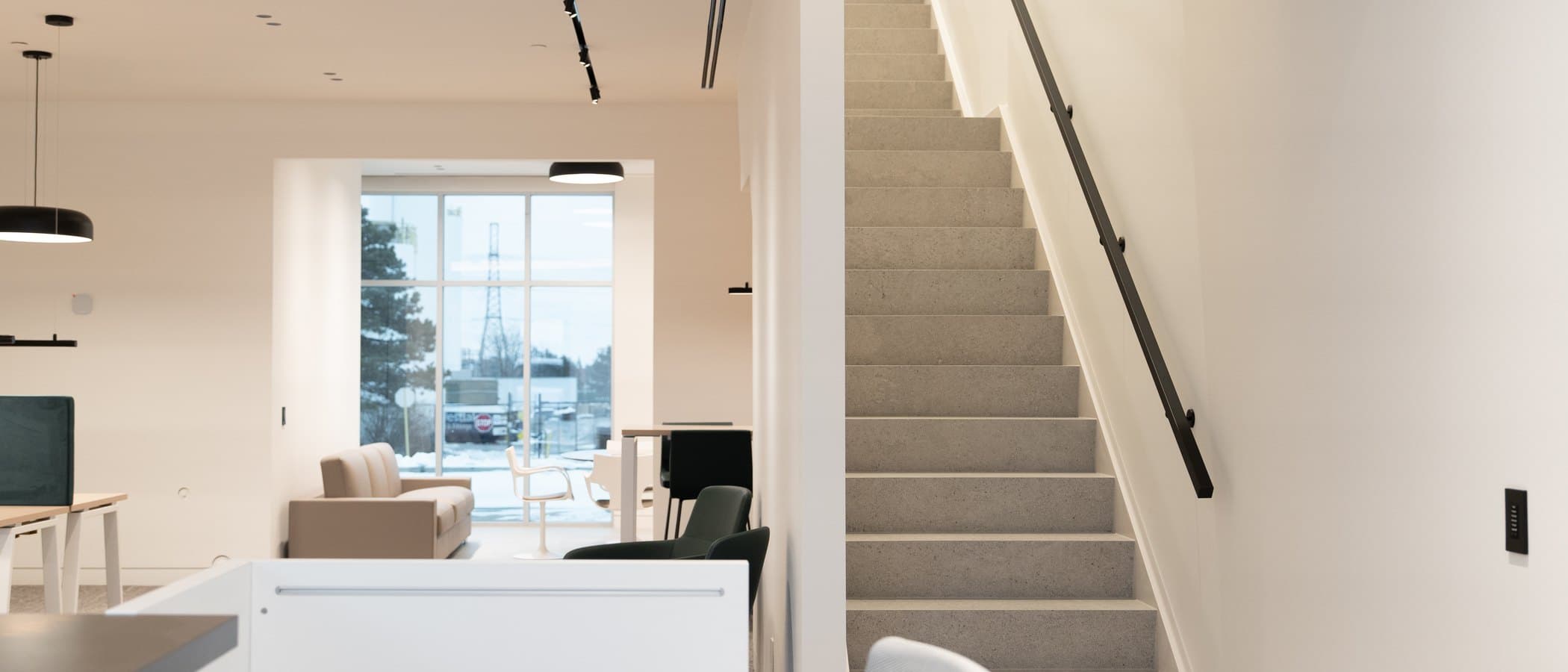 Reception desk in pale millwork beneath a clean ceiling plane with track lighting