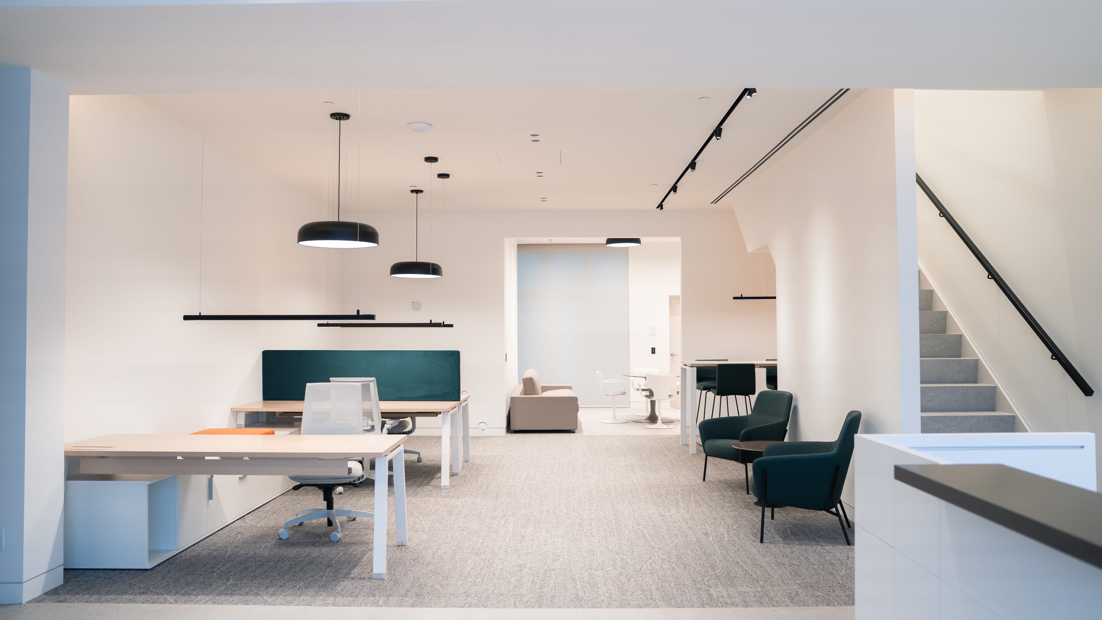 Open office with workstations, a lounge, a staircase and a kitchenette in one wide view