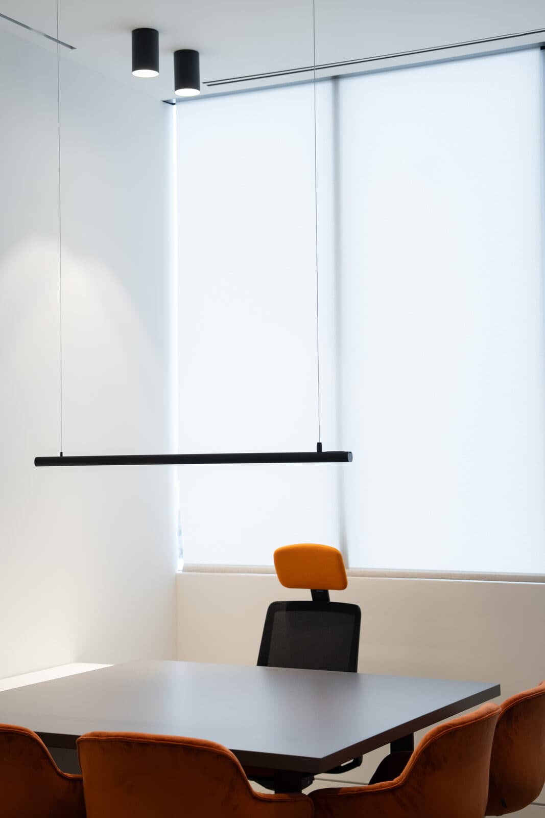 Meeting room corner with orange chairs and roller shades