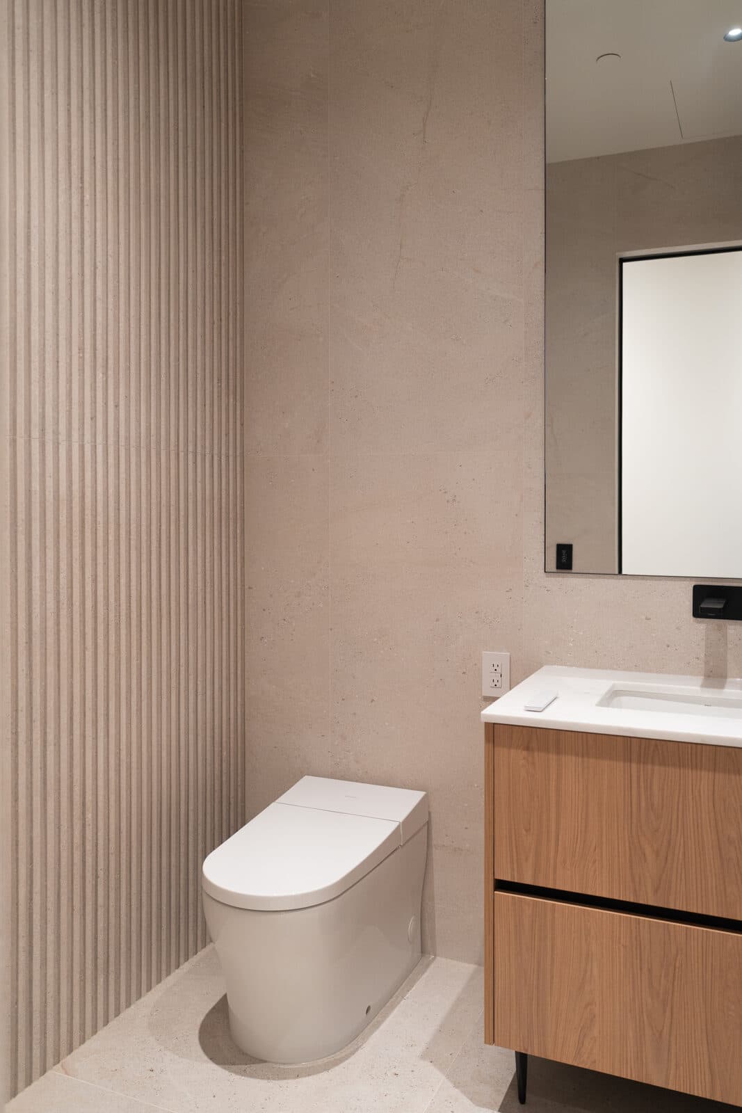 Bathroom with an oak vanity, a mirror and a wall hung toilet