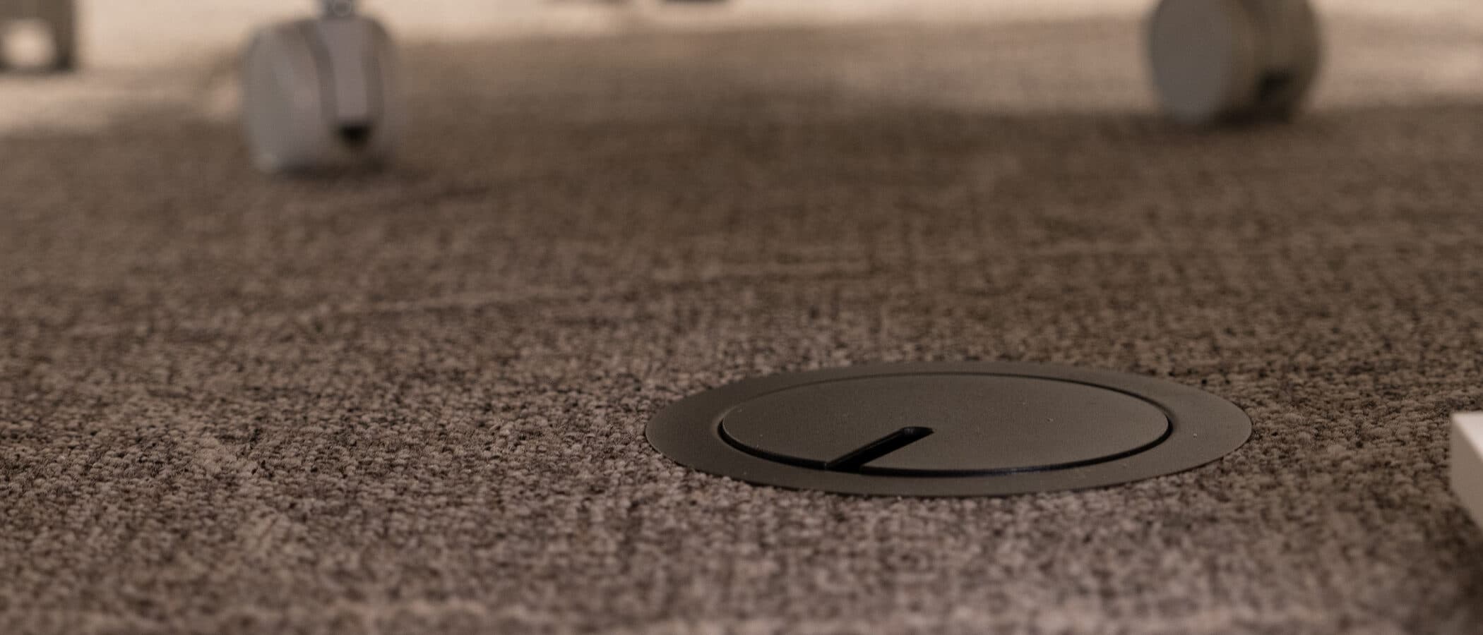 Under desk floor grommet detail in shallow focus