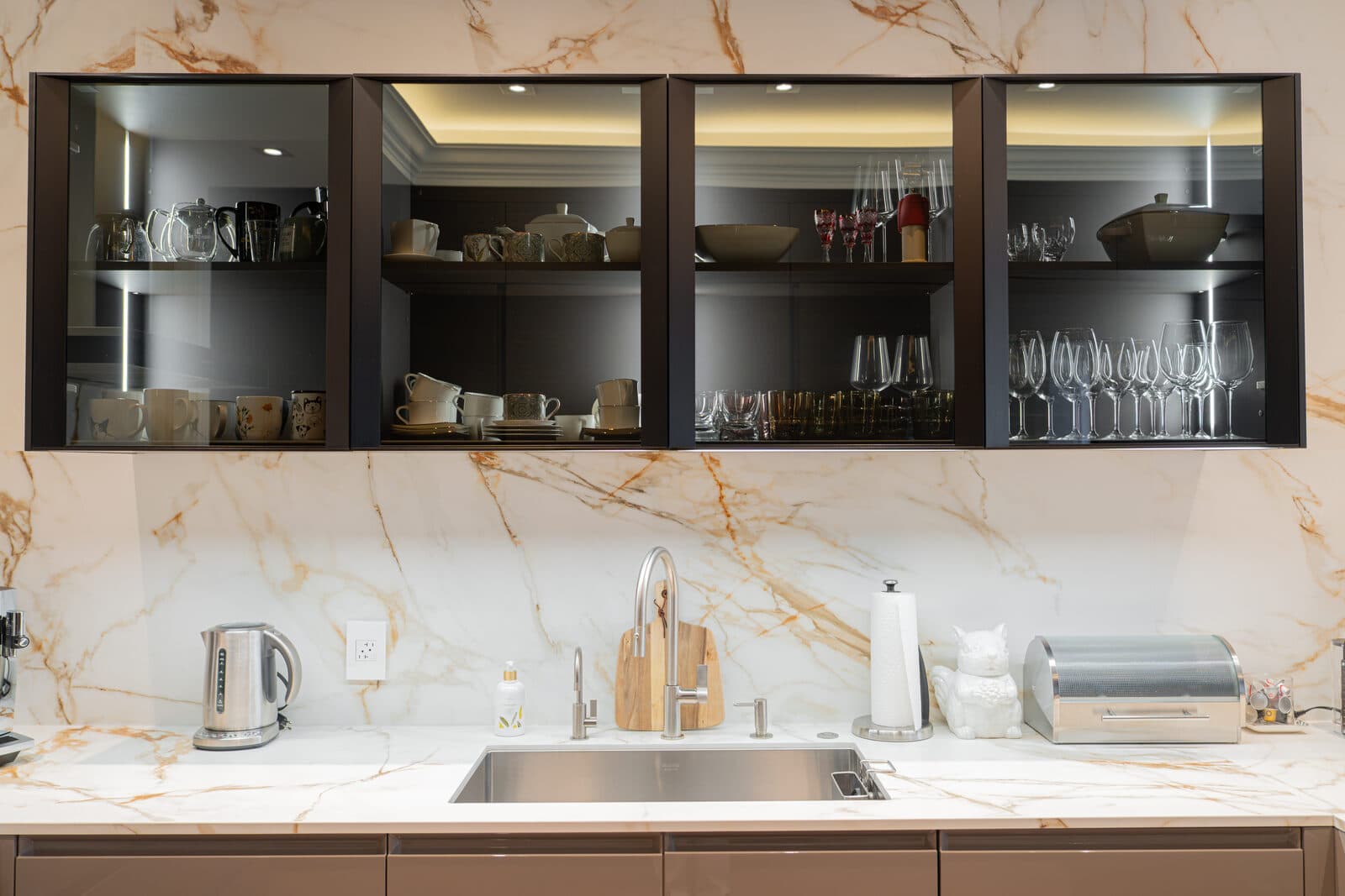 Kitchenette elevation with glass upper cabinets and a marble slab backsplash